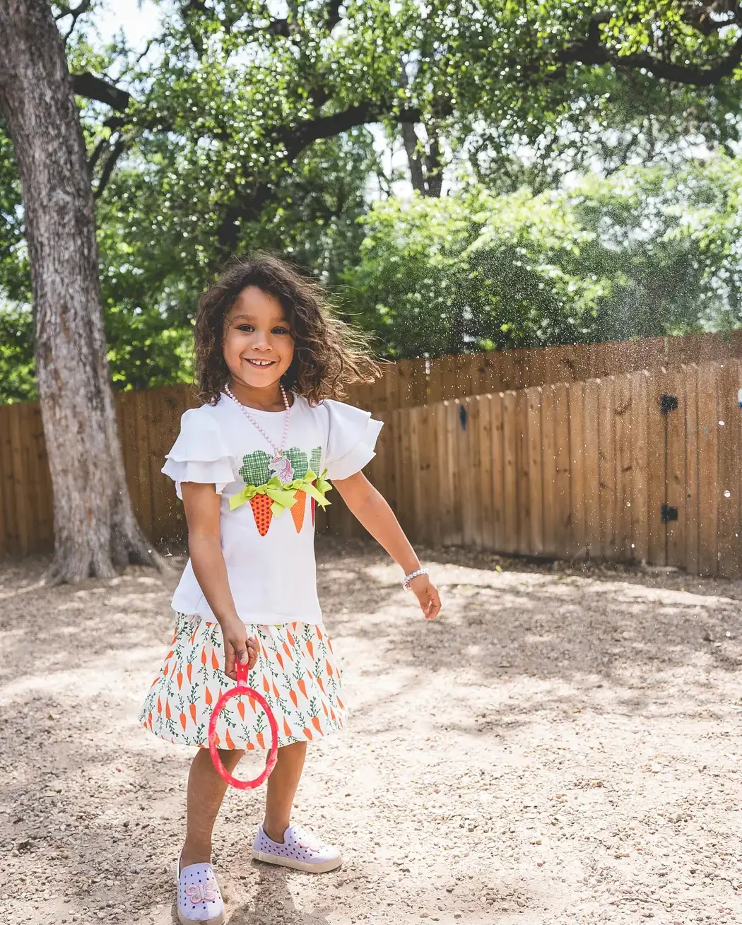 Young child smiling and playing with a ring toss on an outdoor playground.