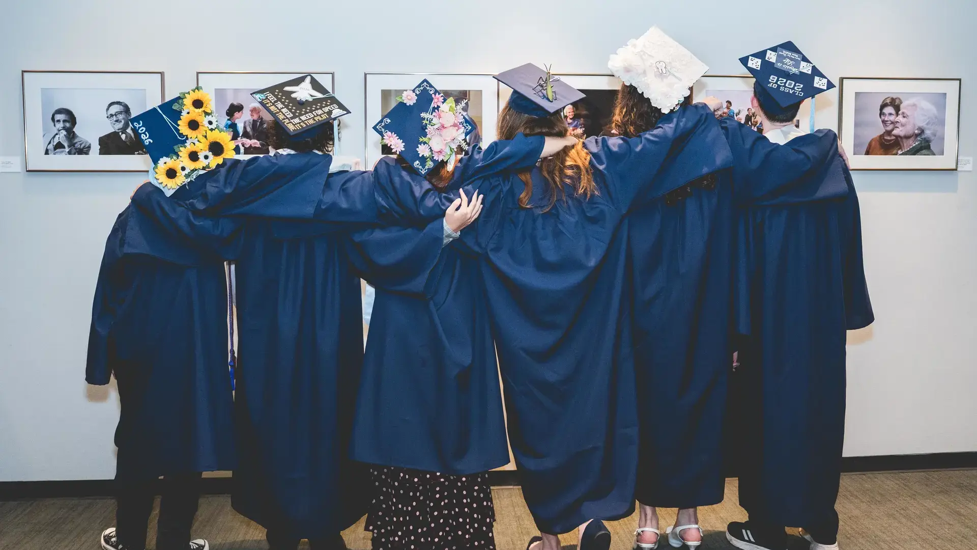 Headwaters School graduates in caps and gowns embracing in a group hug.