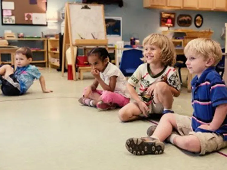 Young children sitting on the floor together during a classroom lesson.