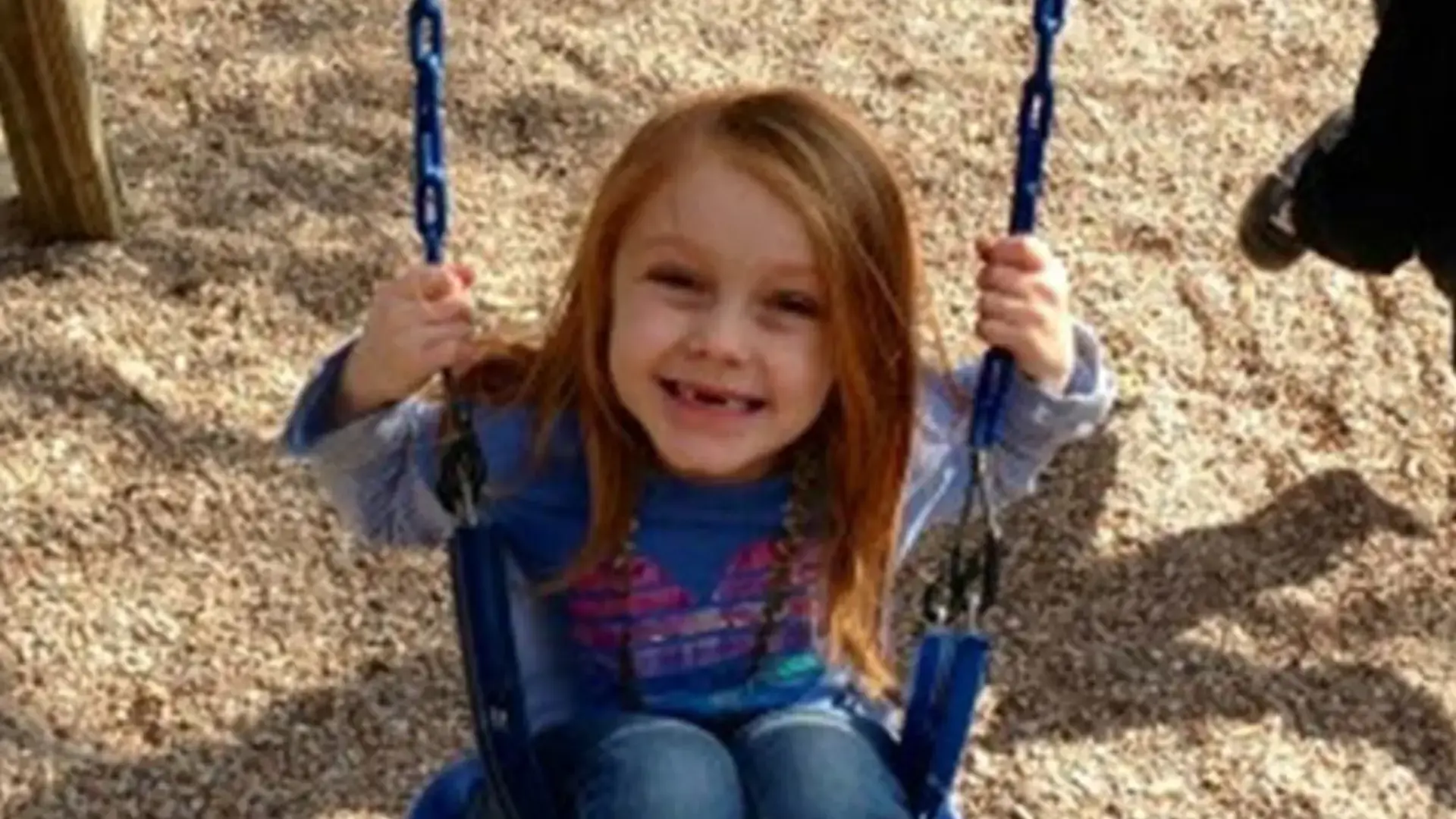 Young child smiling while playing on outdoor playground equipment
