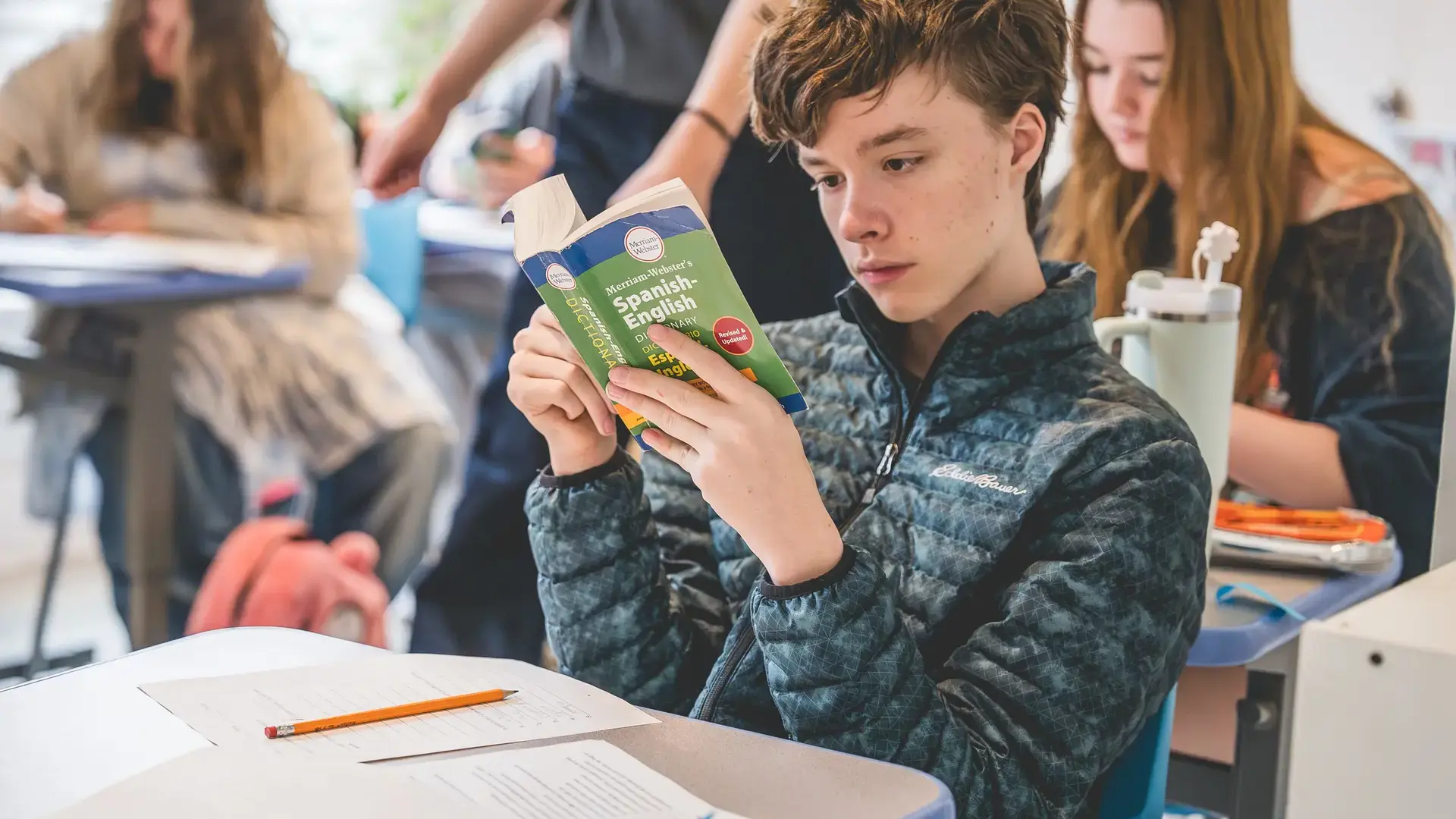 A student reading a book at a desk in class.