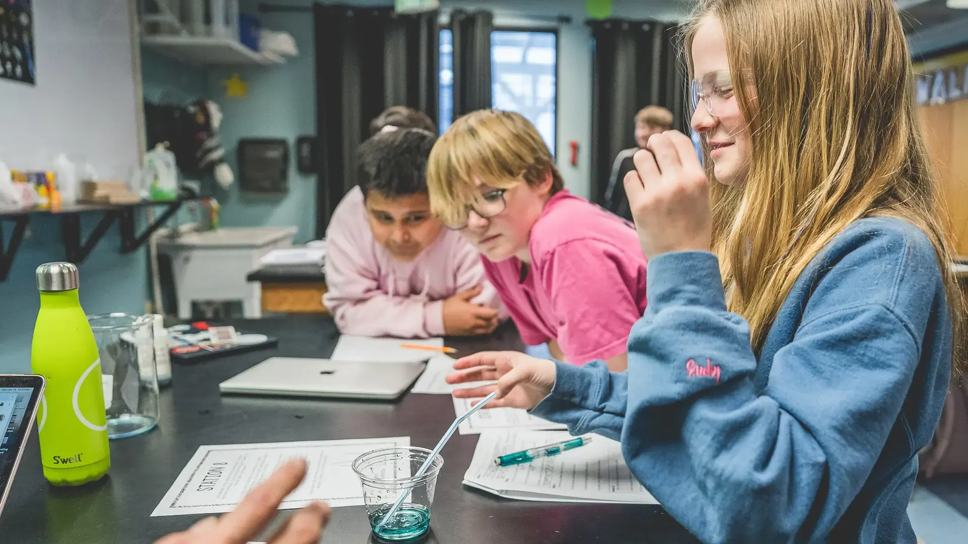 Students working together at a table with a teacher during a classroom activity