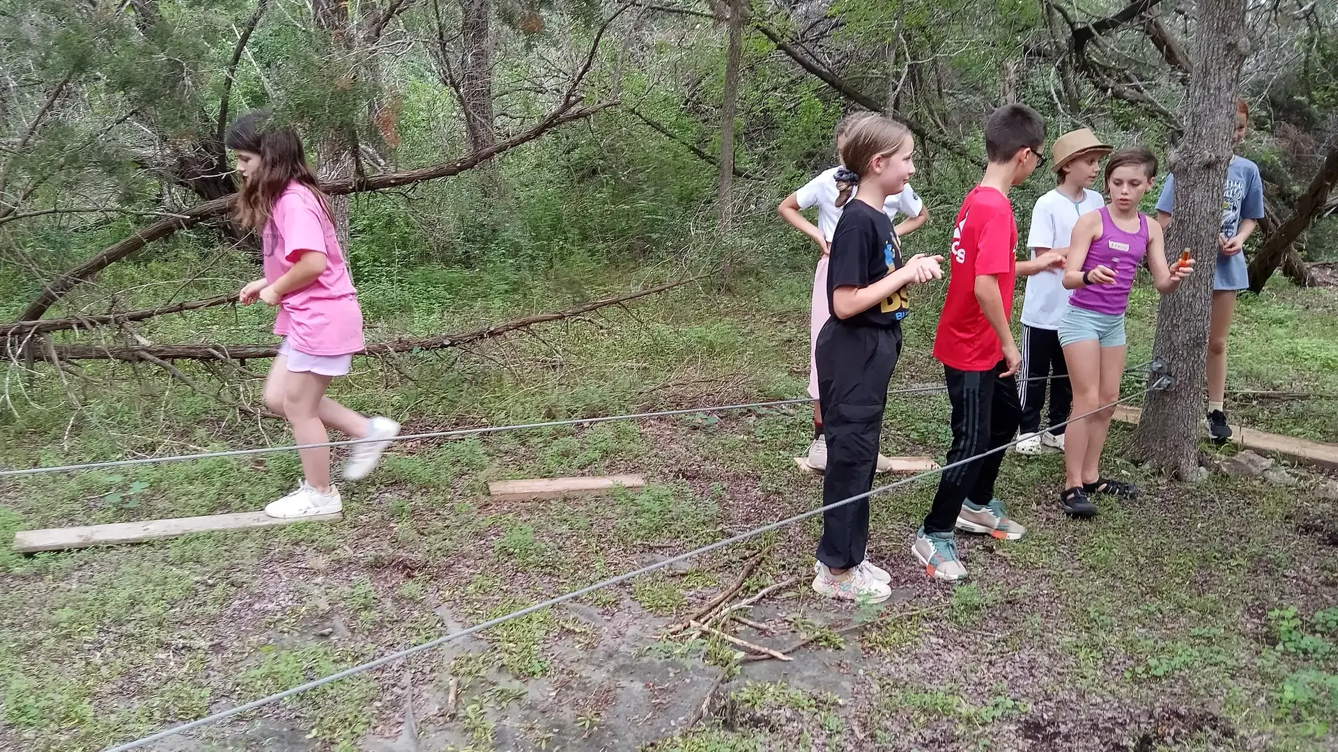 Students balancing across a wooden plank in the Bird's Nest outdoor area.
