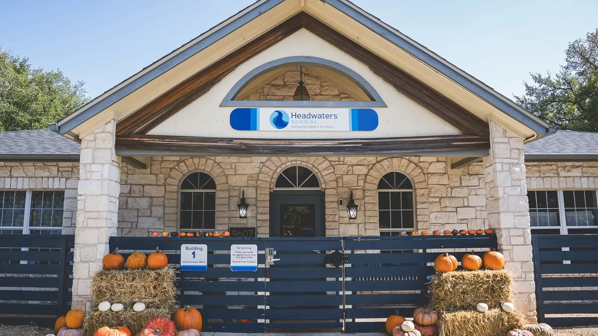 Entrance to a stone Headwaters School building decorated with pumpkins.