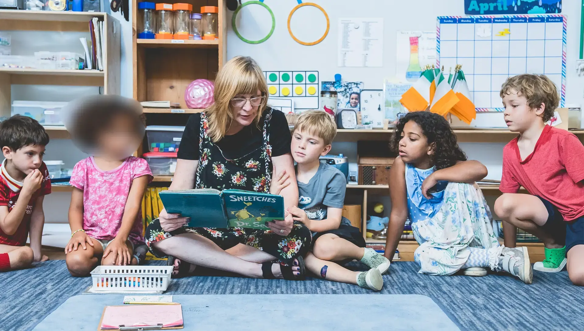 An elementary guide reads aloud to students seated in a circle during classroom story time at Headwaters School’s