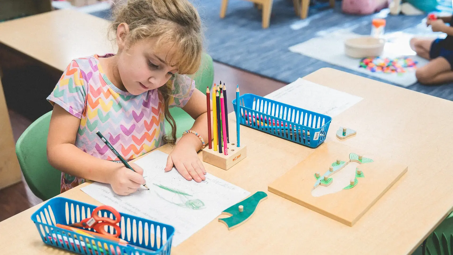 elementary student drawing and writing at her desk.