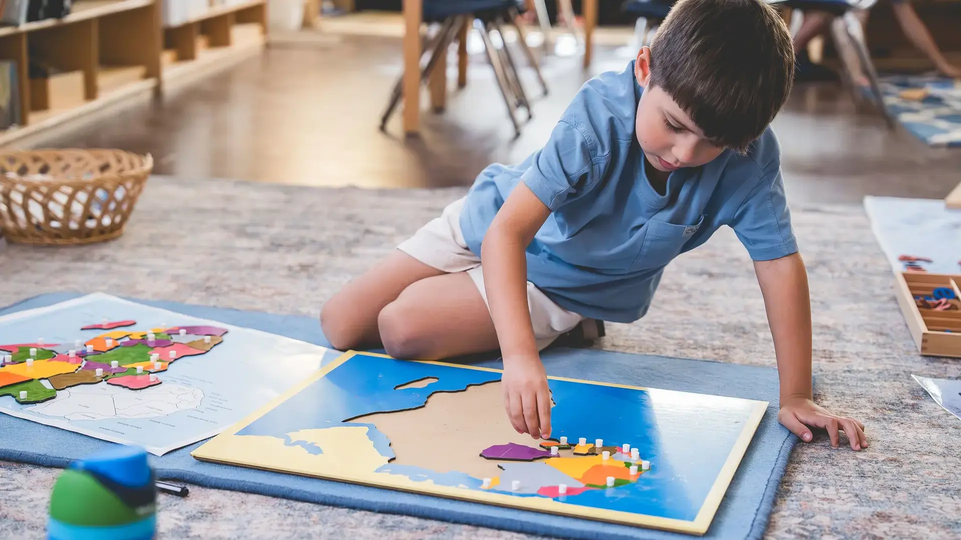 Elementary student completing a Montessori geography puzzle during an independent classroom learning activity.