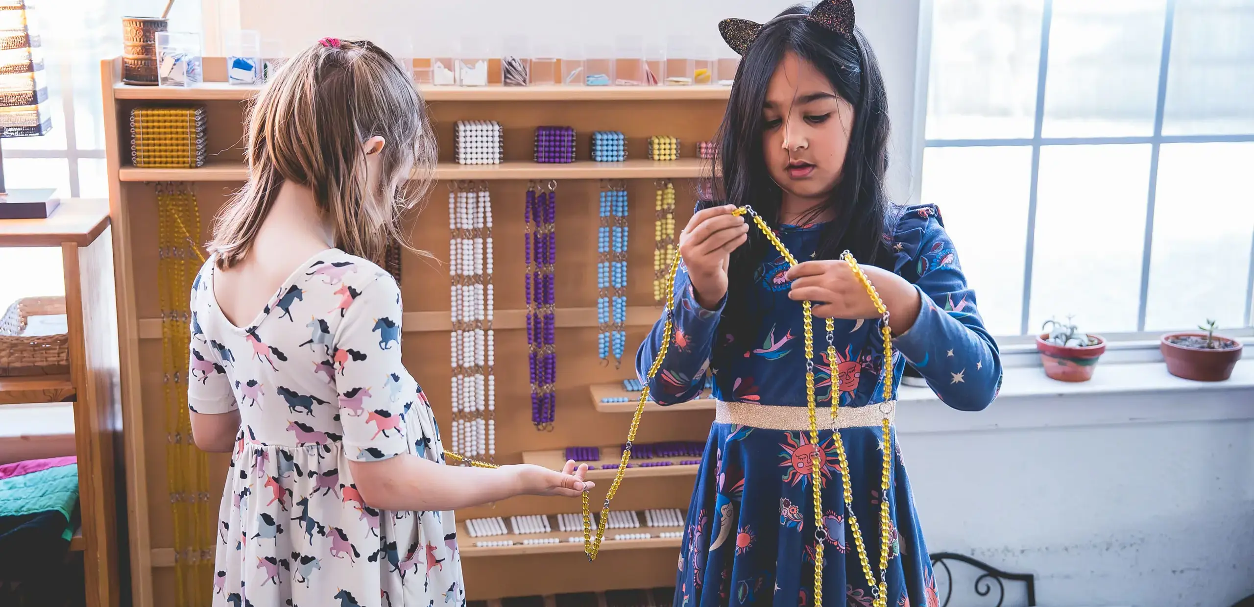 Elementary students working together with Montessori golden bead chains for math practice.