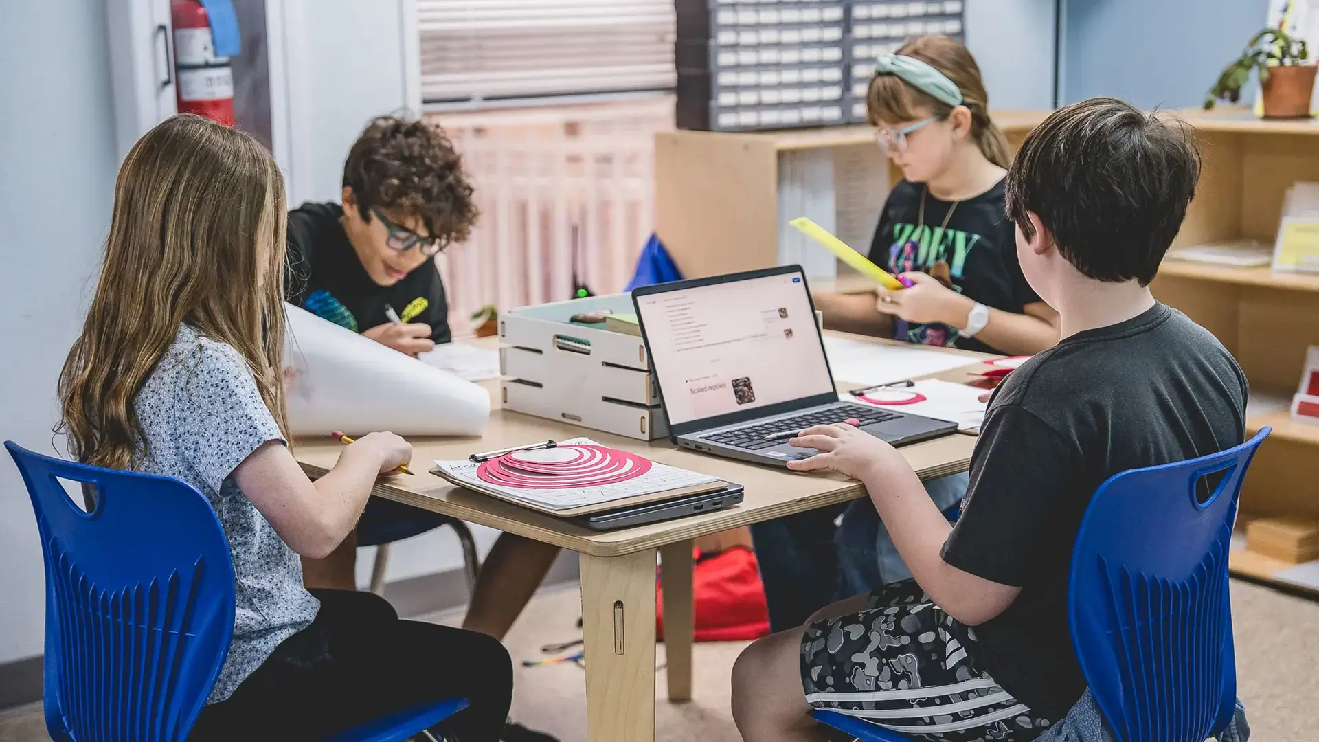elementary students collaborating on a project together at a classroom table.