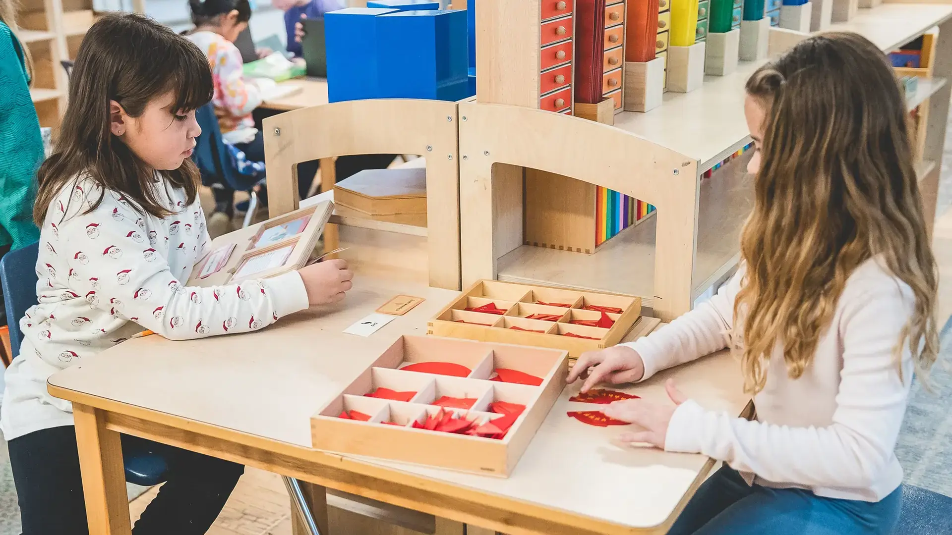 elementary students working together with Montessori fraction materials at a table.