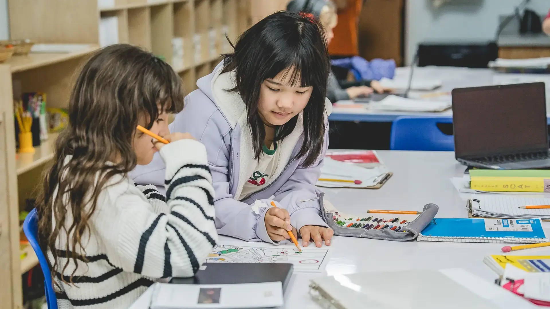 elementary students working together on an activity at a desk.