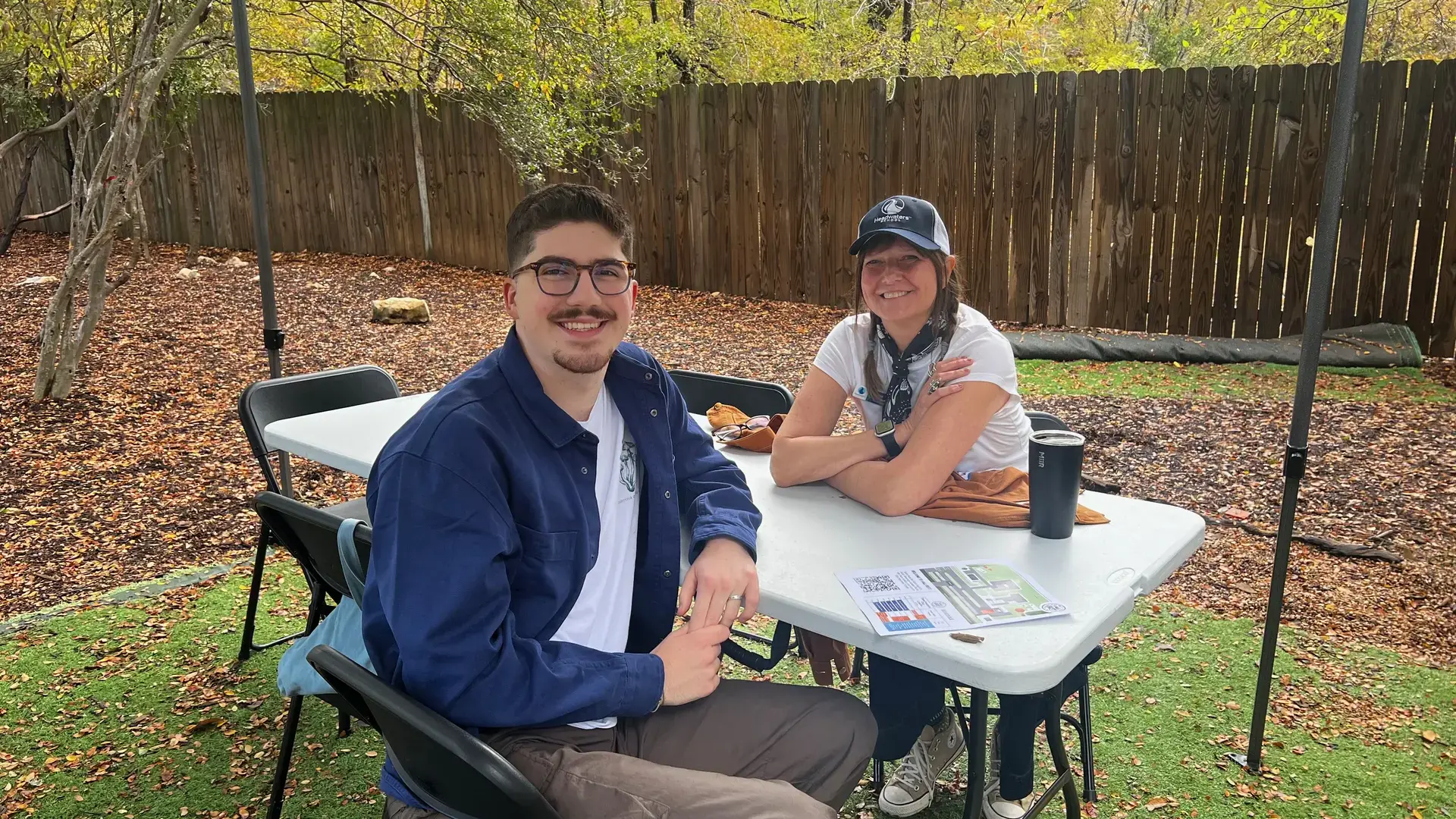 Two alumni sitting together at an outdoor table during a Fall Fest event.