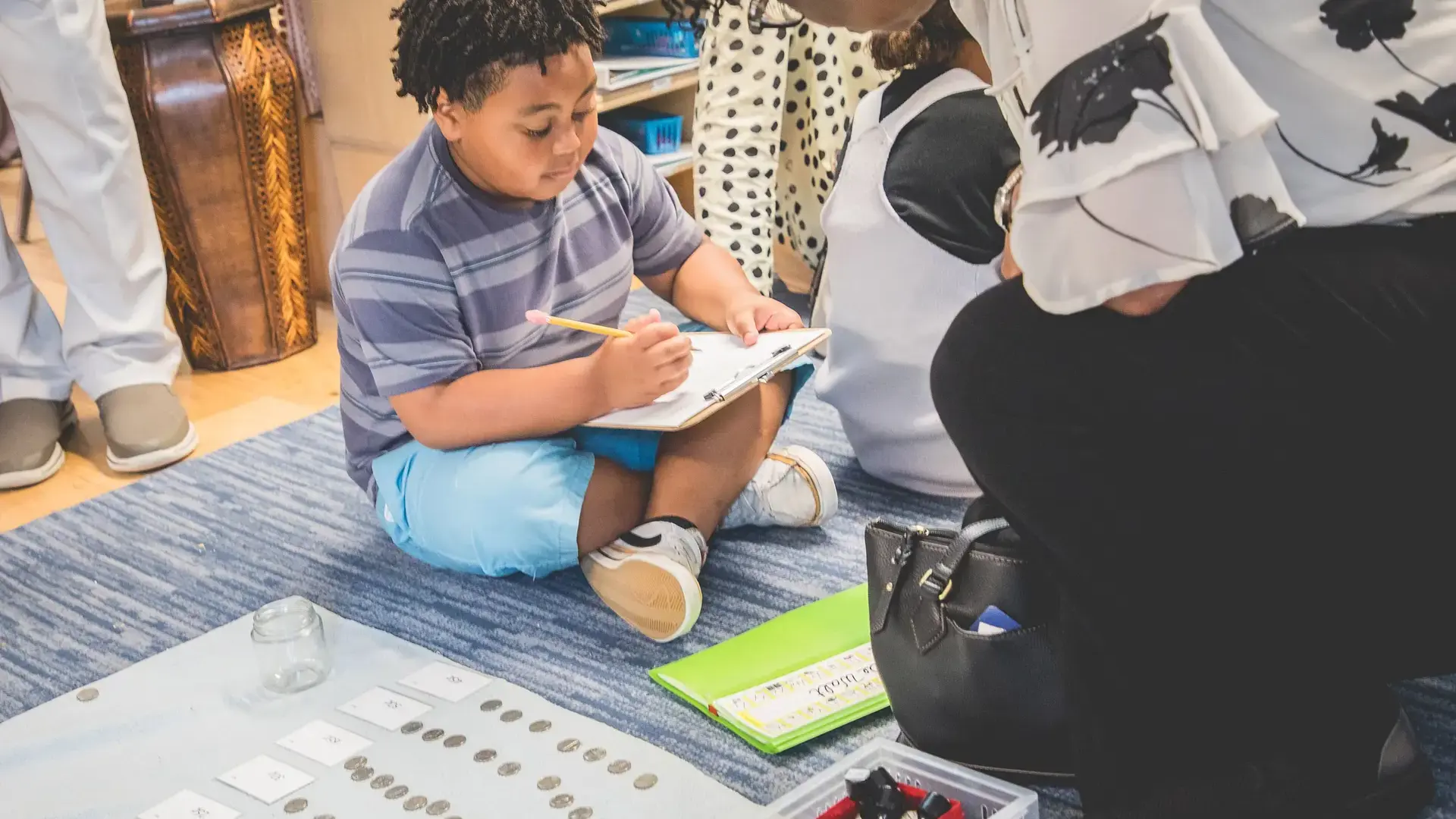 a young child working on a hands-on activity while seated on the floor.