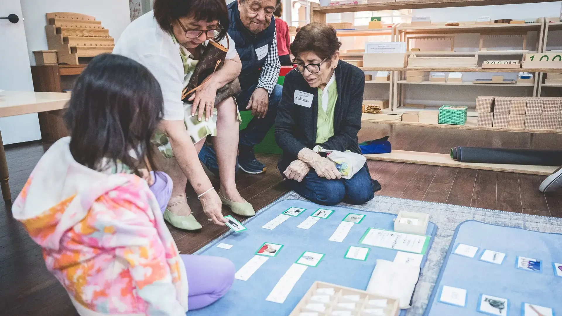 elementary students working with a Montessori language material on the floor during Grandparents and Special Friends Day.