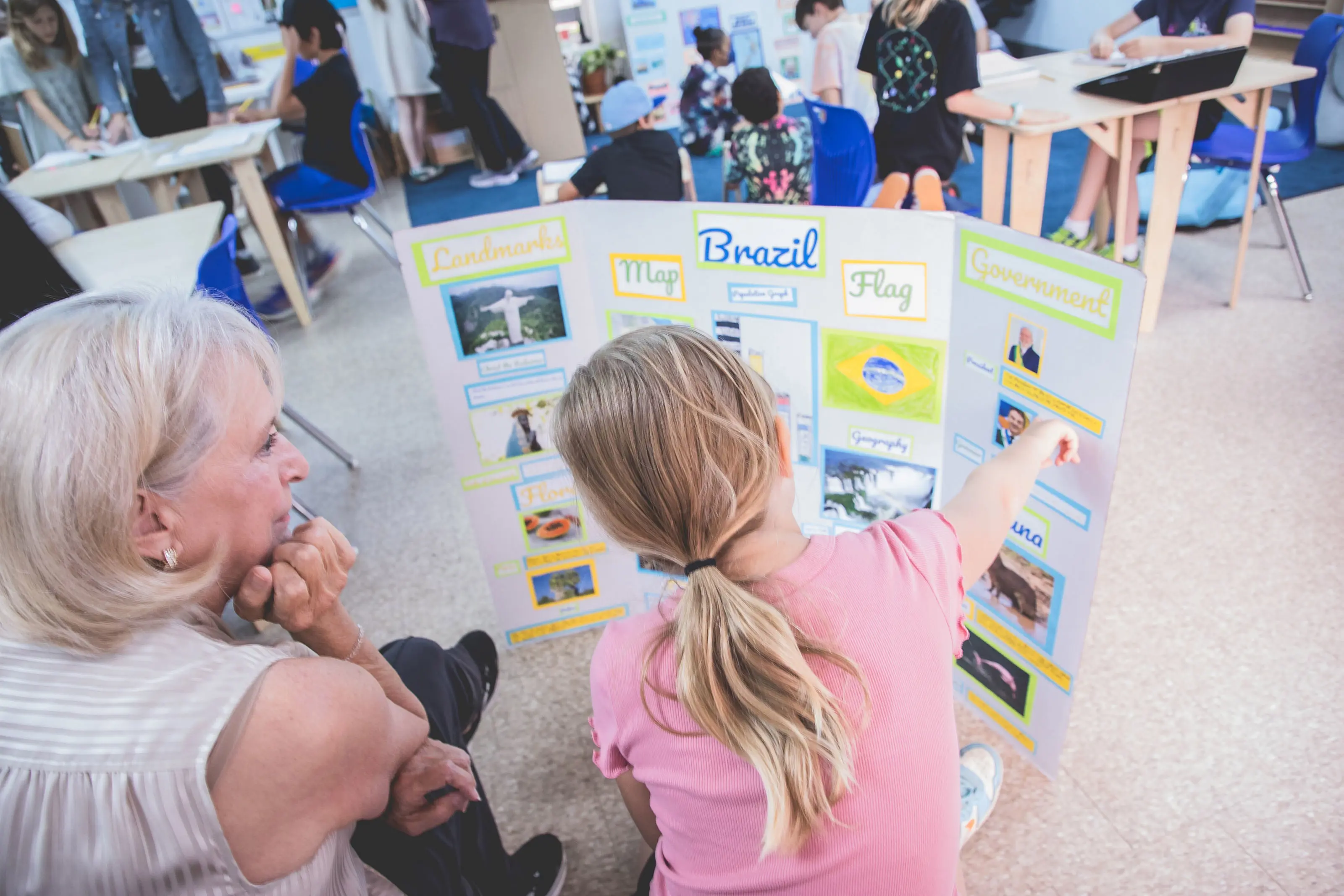 elementary student presenting her Brazil project poster to a grandparent during Grandparents and Special Friends Day.