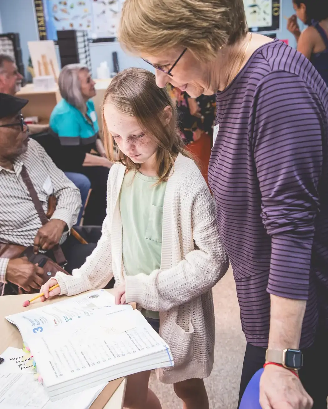 elementary student sharing her workbook with a grandparent during Grandparents and Special Friends Day.
