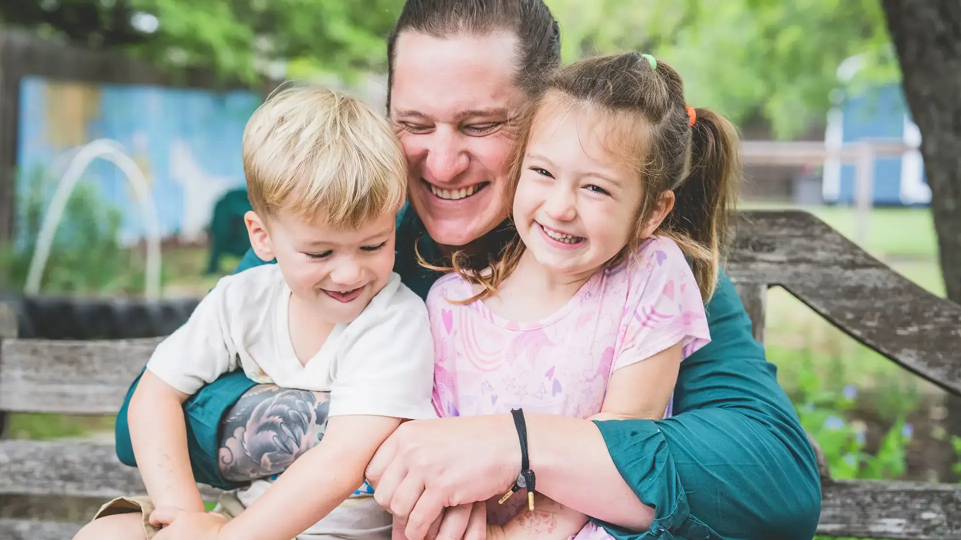grandparent hugging two young children outdoors.
