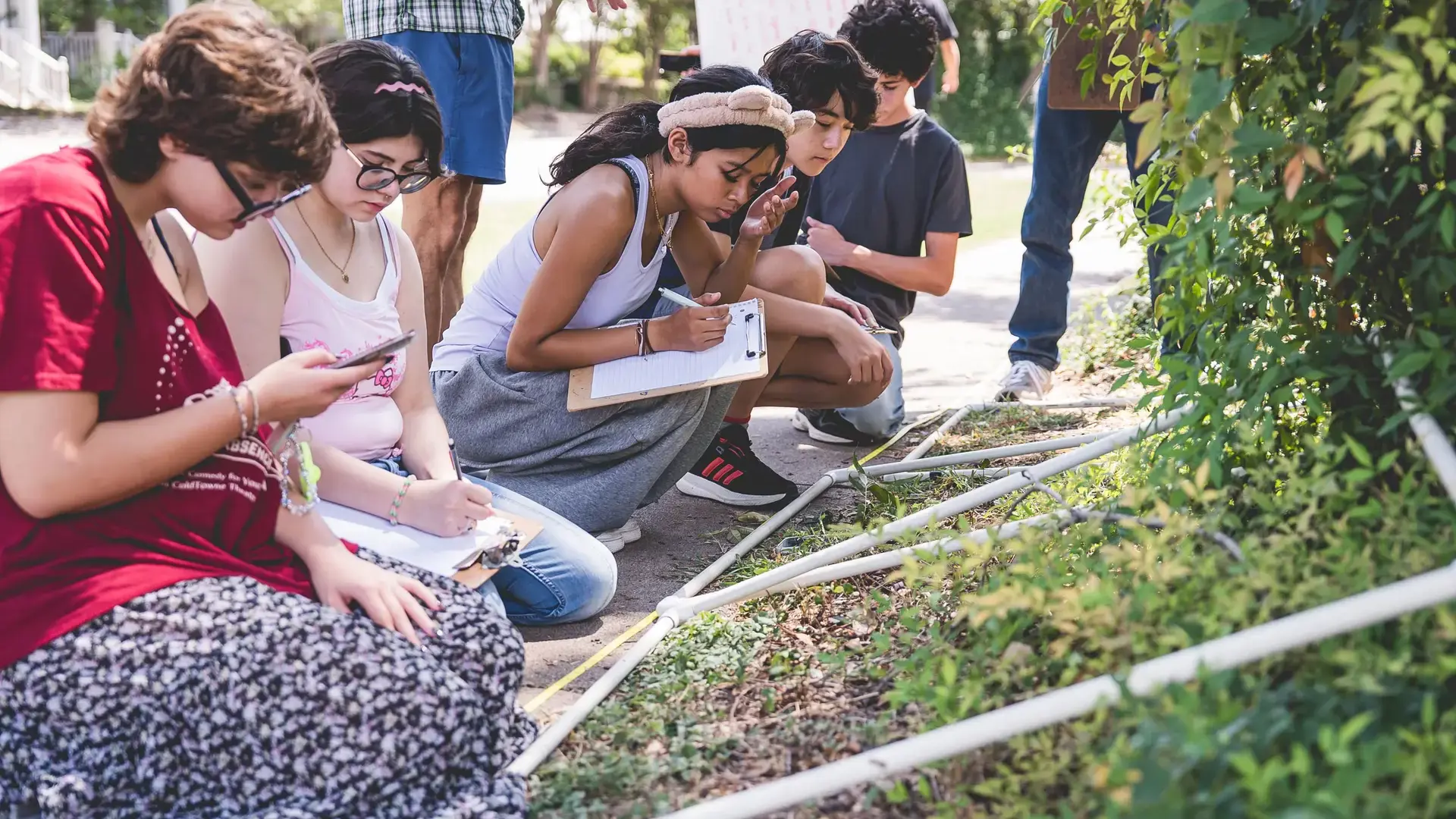 family and students examining plants together outdoors during a City as Classroom activity.