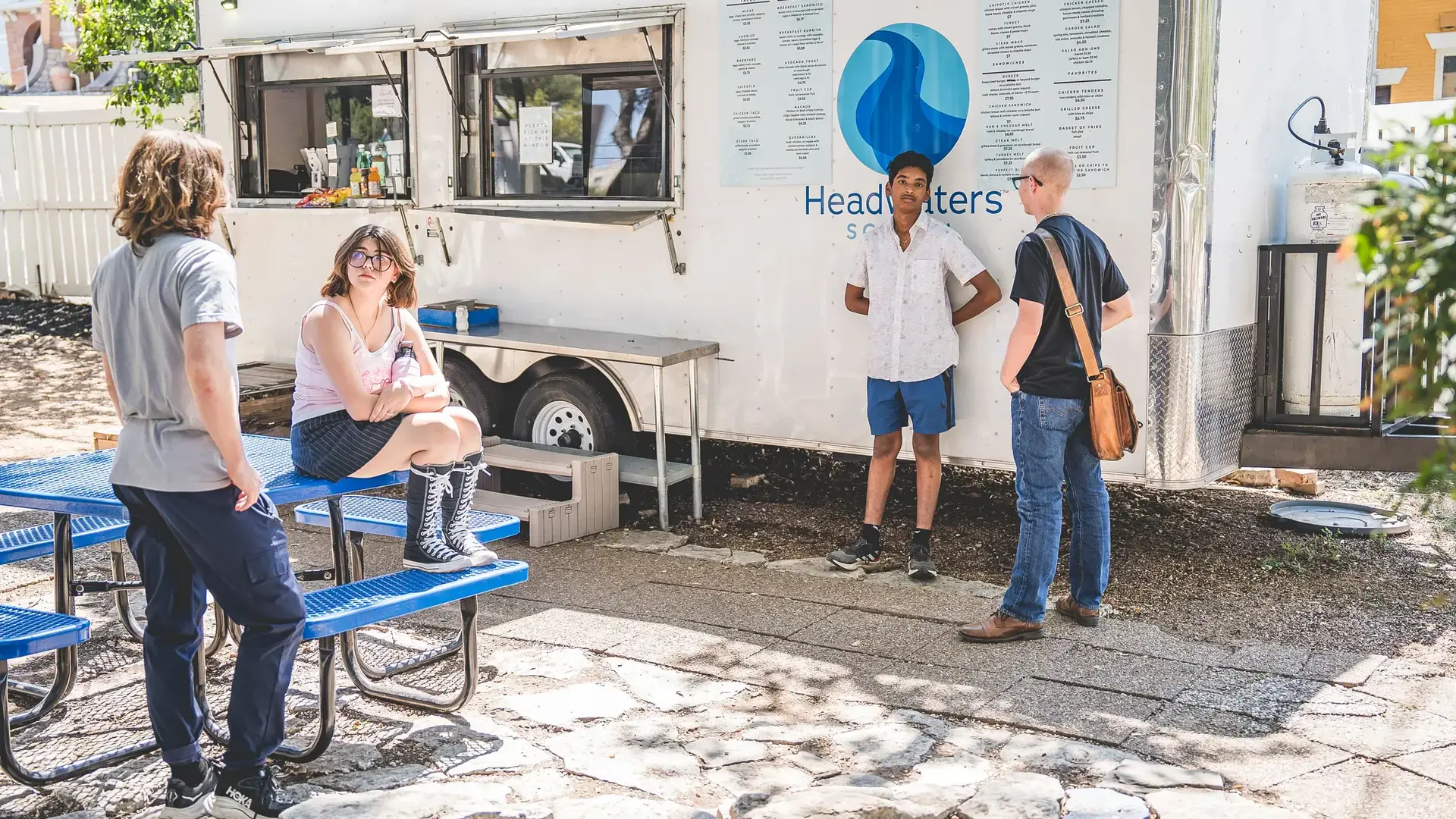 High school students and staff gathered outside near a food truck during a campus event.