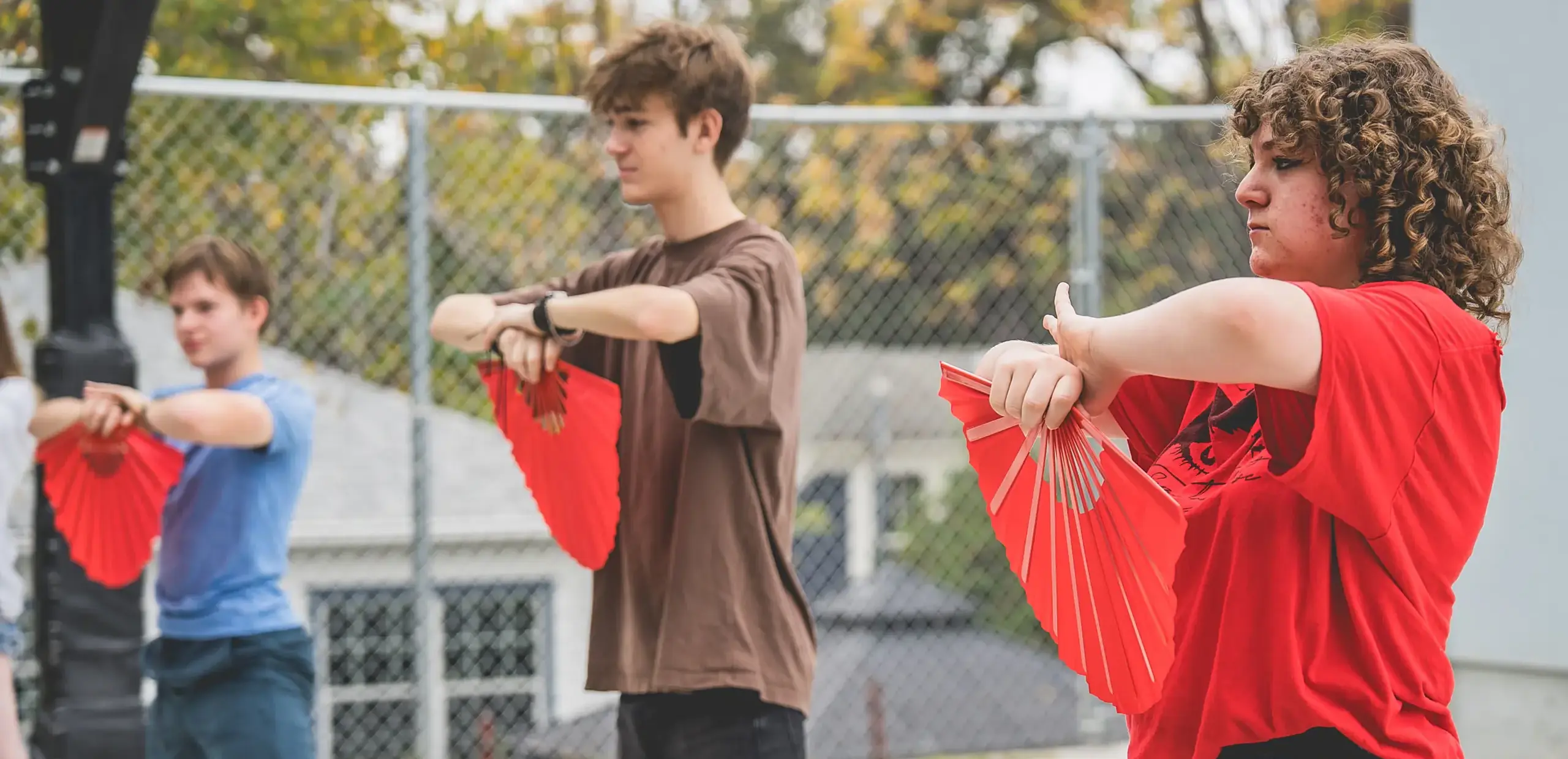 high school students practicing tai chi fan dance outdoors during Mandarin language class.