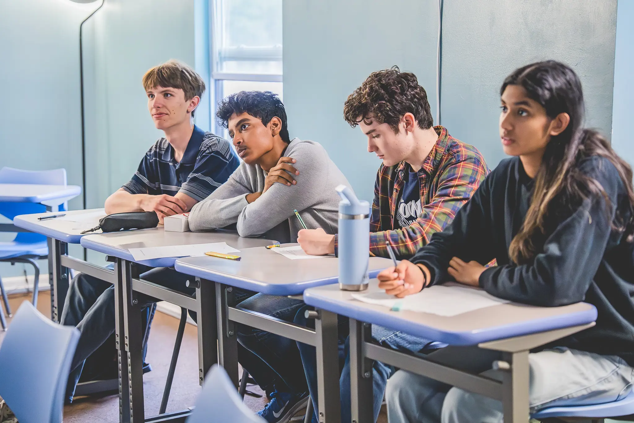 high school students seated at desks listening attentively during a classroom discussion.