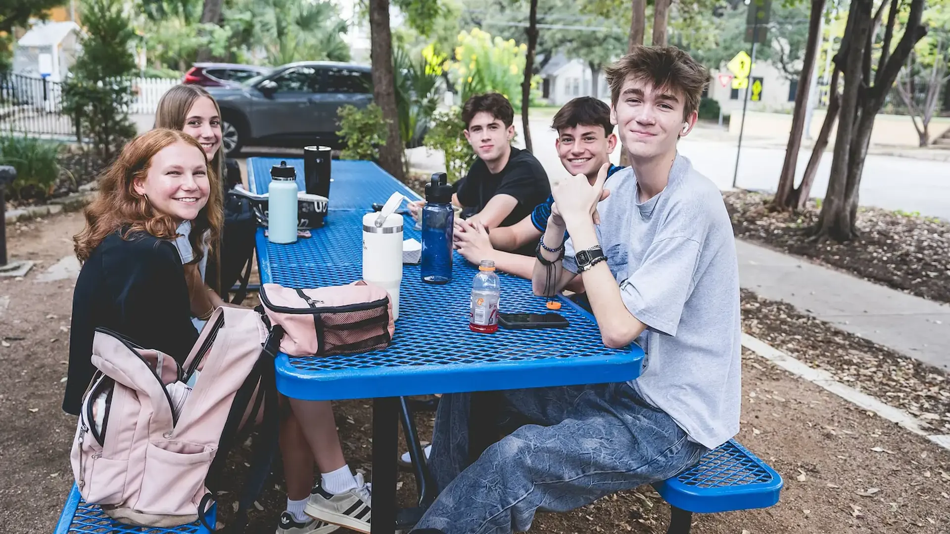 high school students sitting together at an outdoor picnic table during lunch.