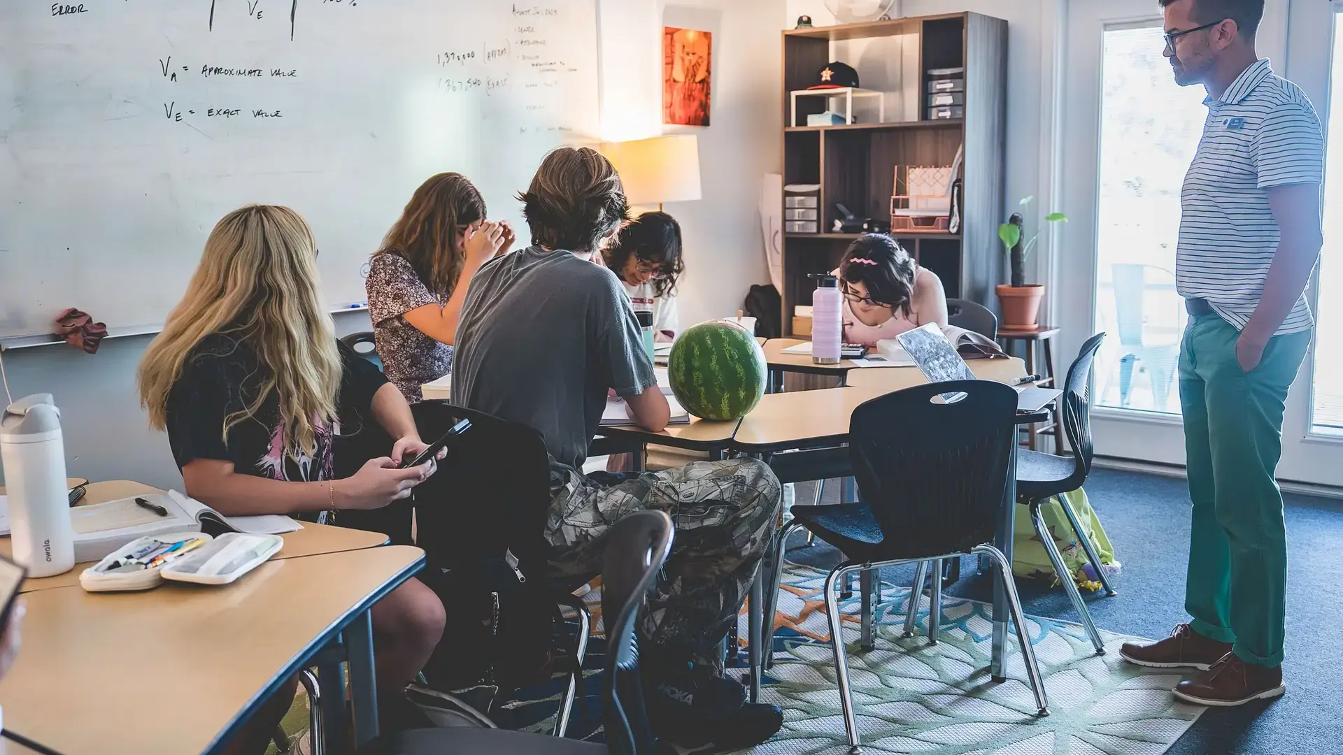 High school students participating in a collaborative math lesson with their teacher in the classroom.
