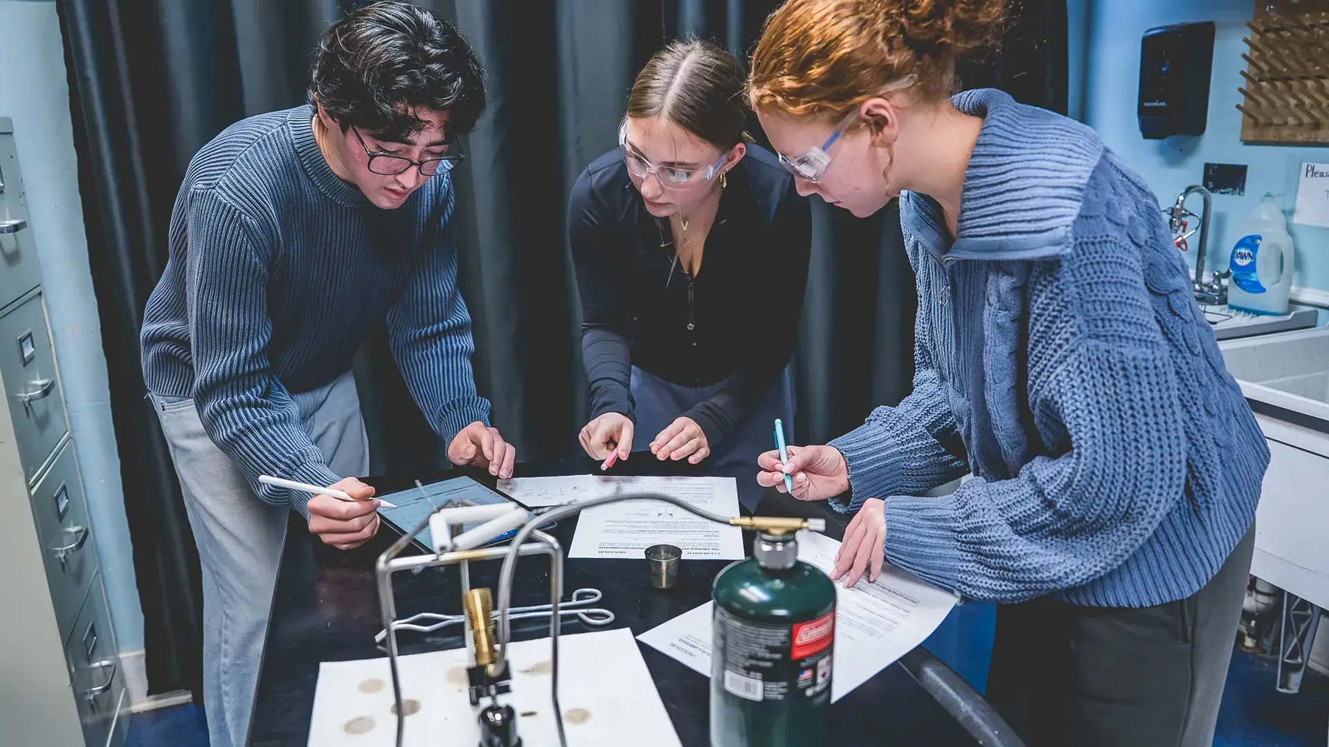 High school students gathered around a lab table conducting a science experiment.