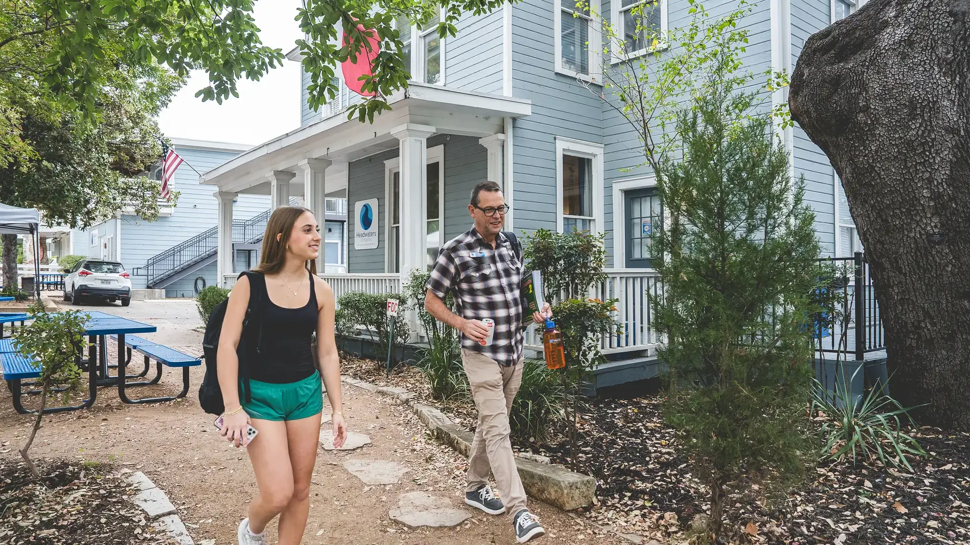 A student and staff member walking together outside a River Campus building.