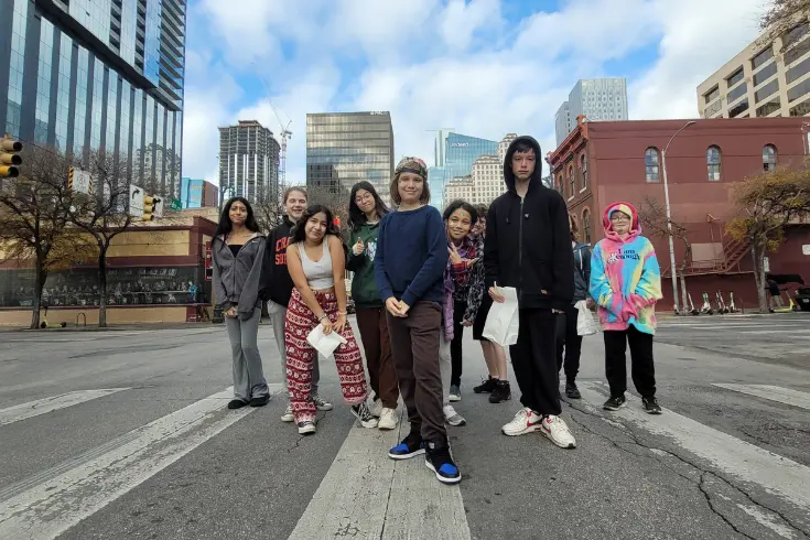 high school students standing together in a downtown Austin crosswalk with high-rise buildings in the background.