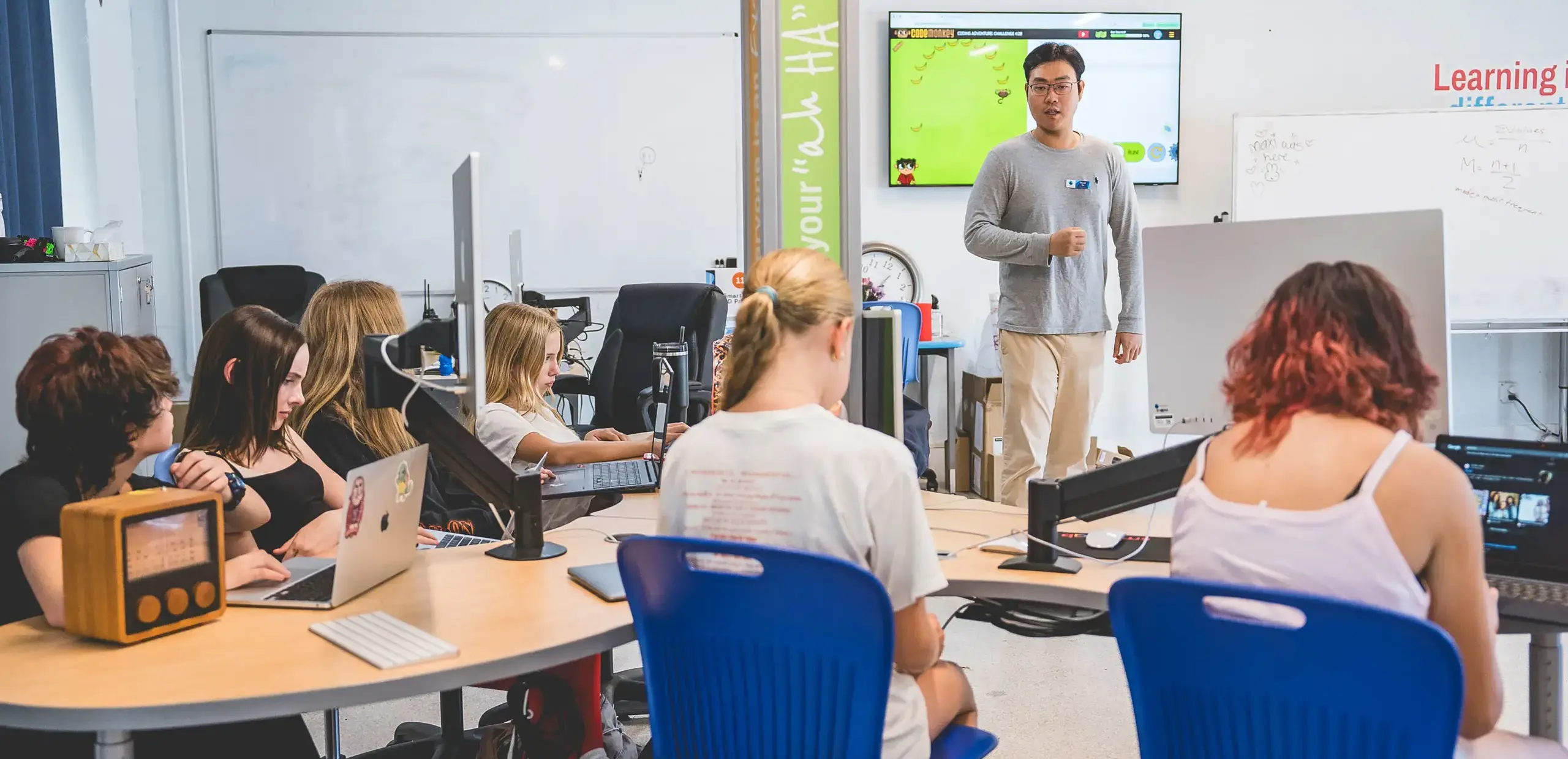 middle school students working on laptops in a Smart Lab STEM classroom while a teacher leads a coding lesson.
