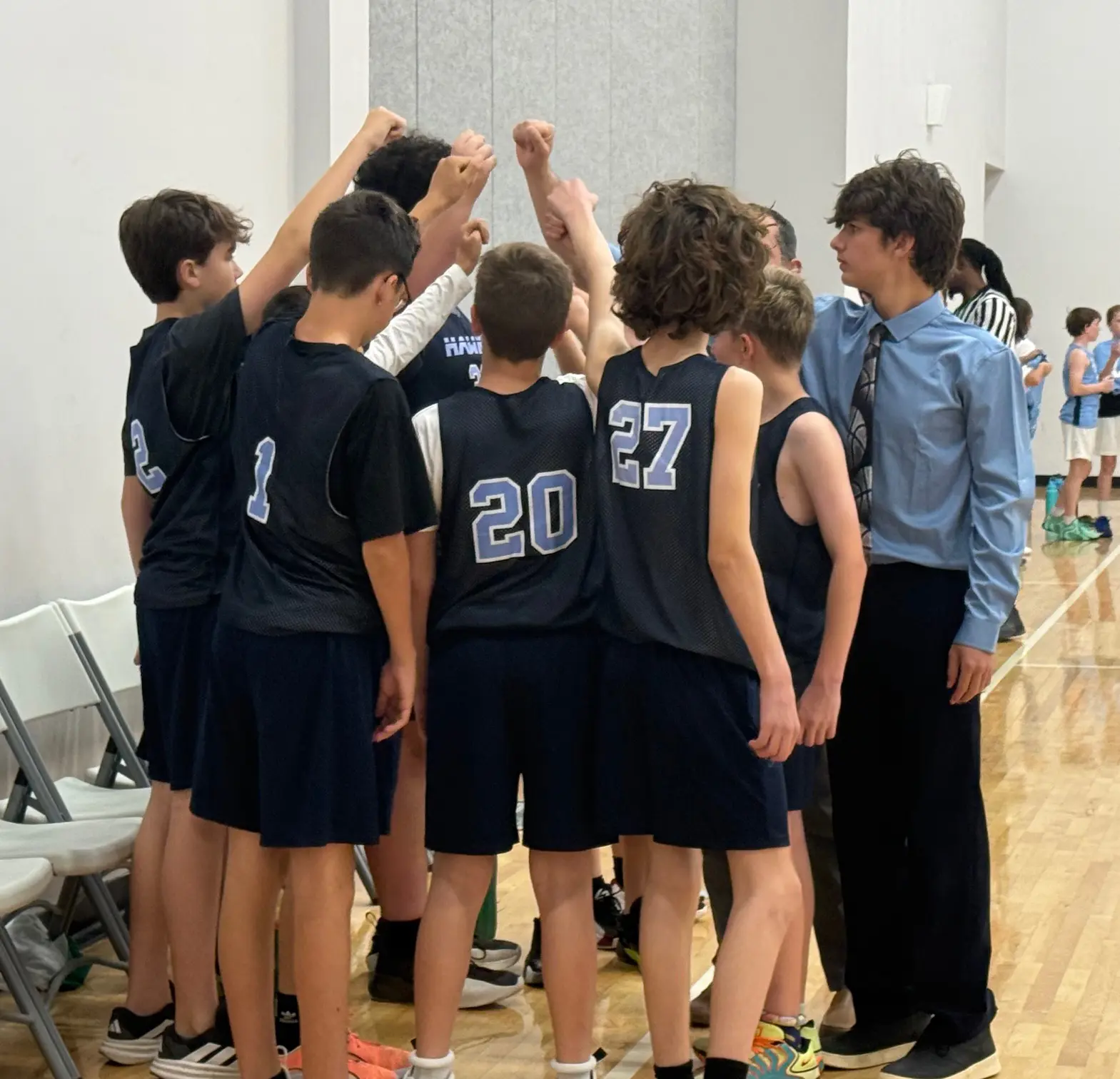 Headwaters Middle School boys basketball team gathers in a huddle with their coach during a game in the school gym.