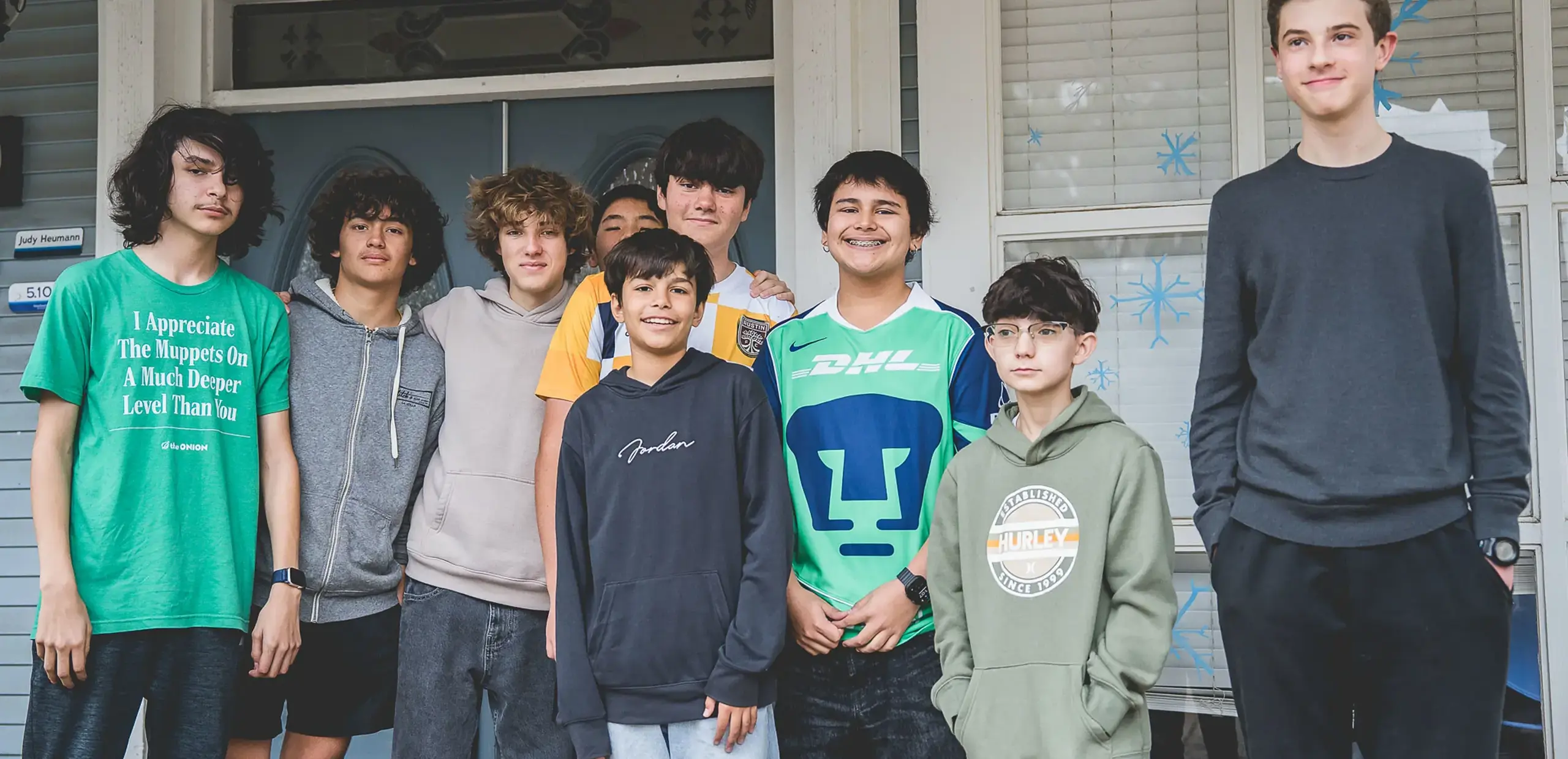 Group of middle school boys smiling together on a front porch.