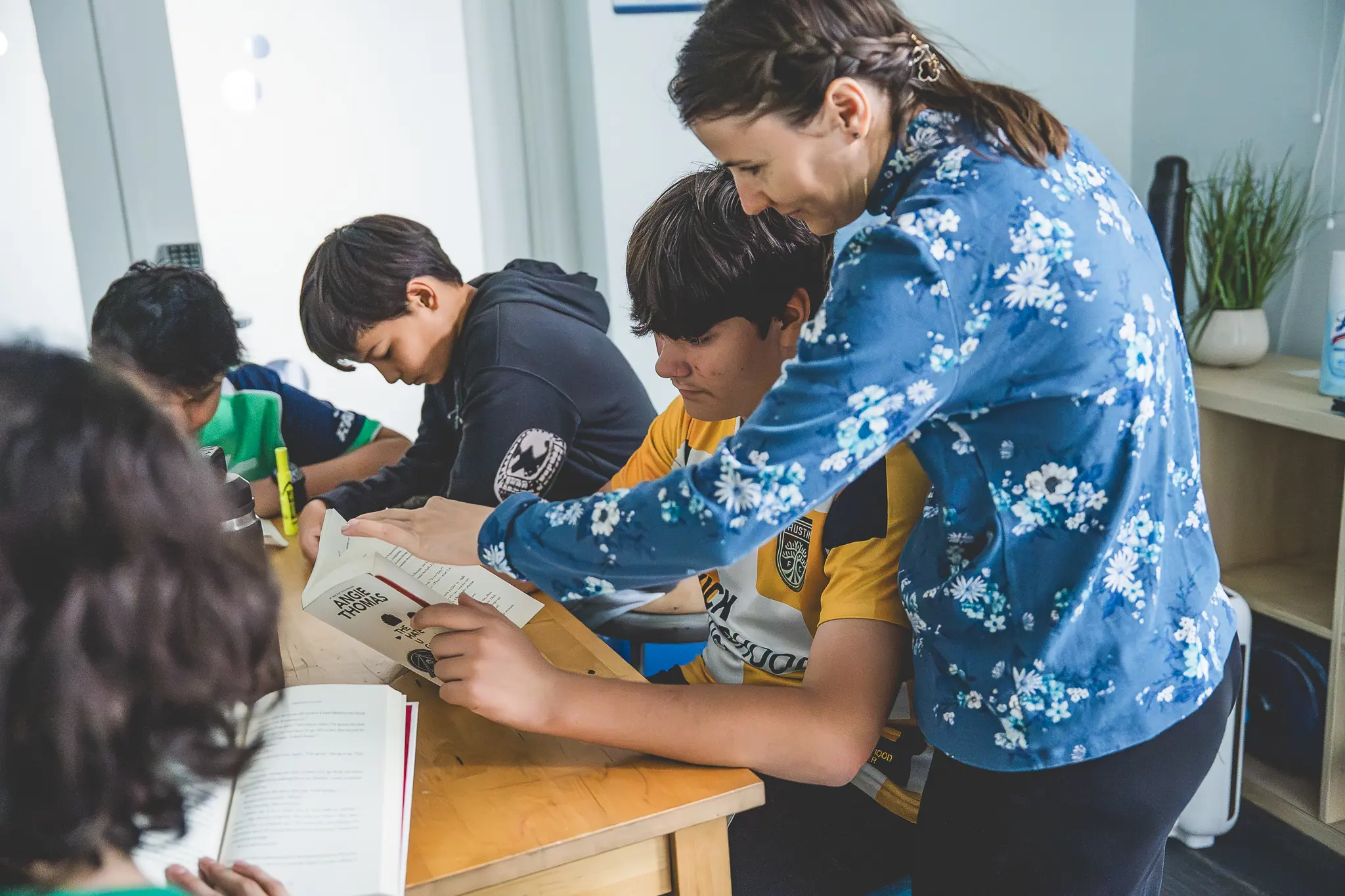 Teacher helping middle school students analyze a text together during class.