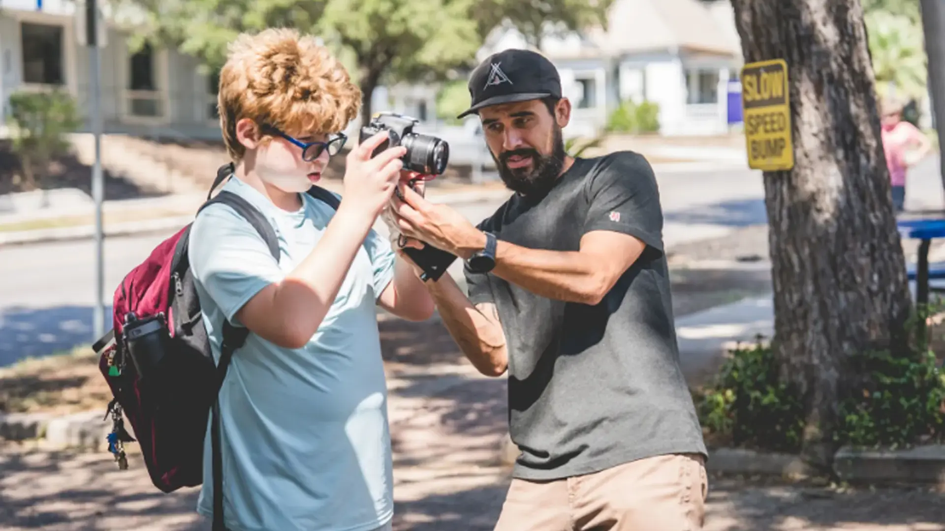 a teacher guiding a student using a camera outdoors.