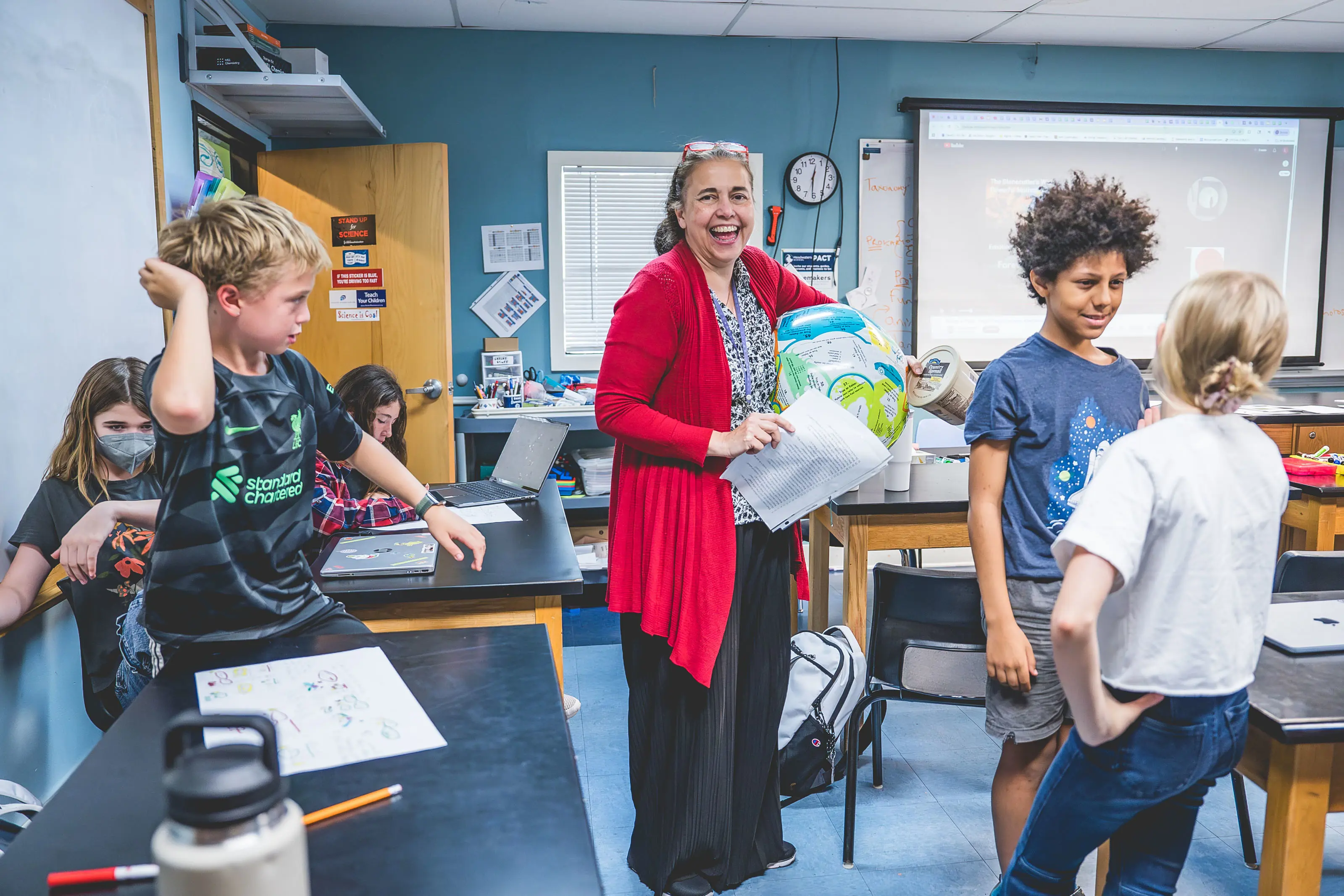 middle school students working together in the science lab with their teacher.