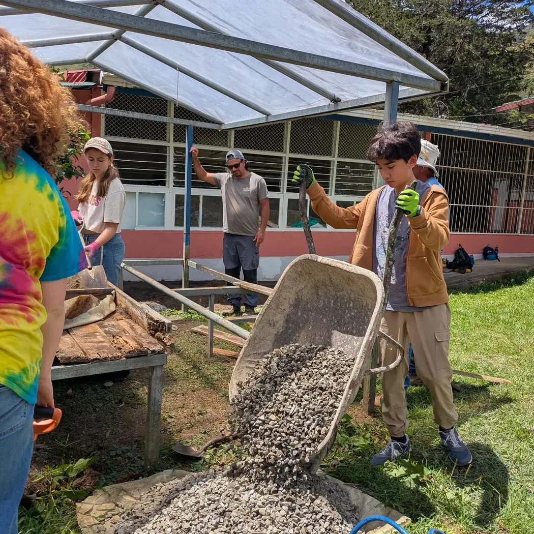 Middle school student pouring gravel during service project in Costa Rica.