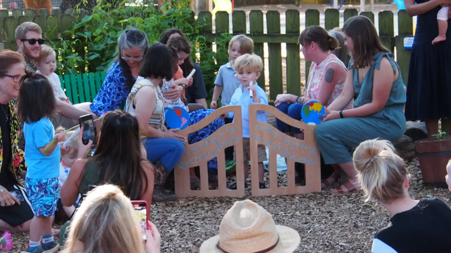 Families and students gathered outdoors on benches during a graduation celebration.