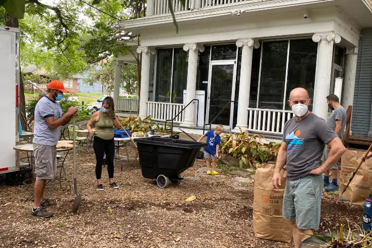 parent volunteers wearing masks doing yard work and gardening outside a school building