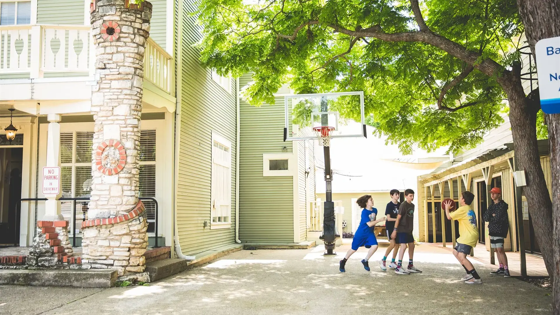 Students playing basketball outdoors near school buildings.