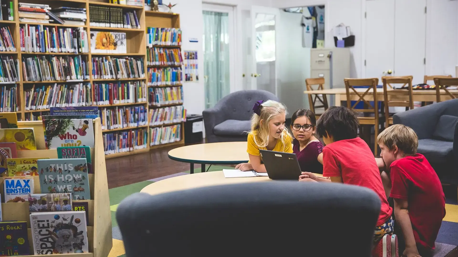 students sharing a laptop on library