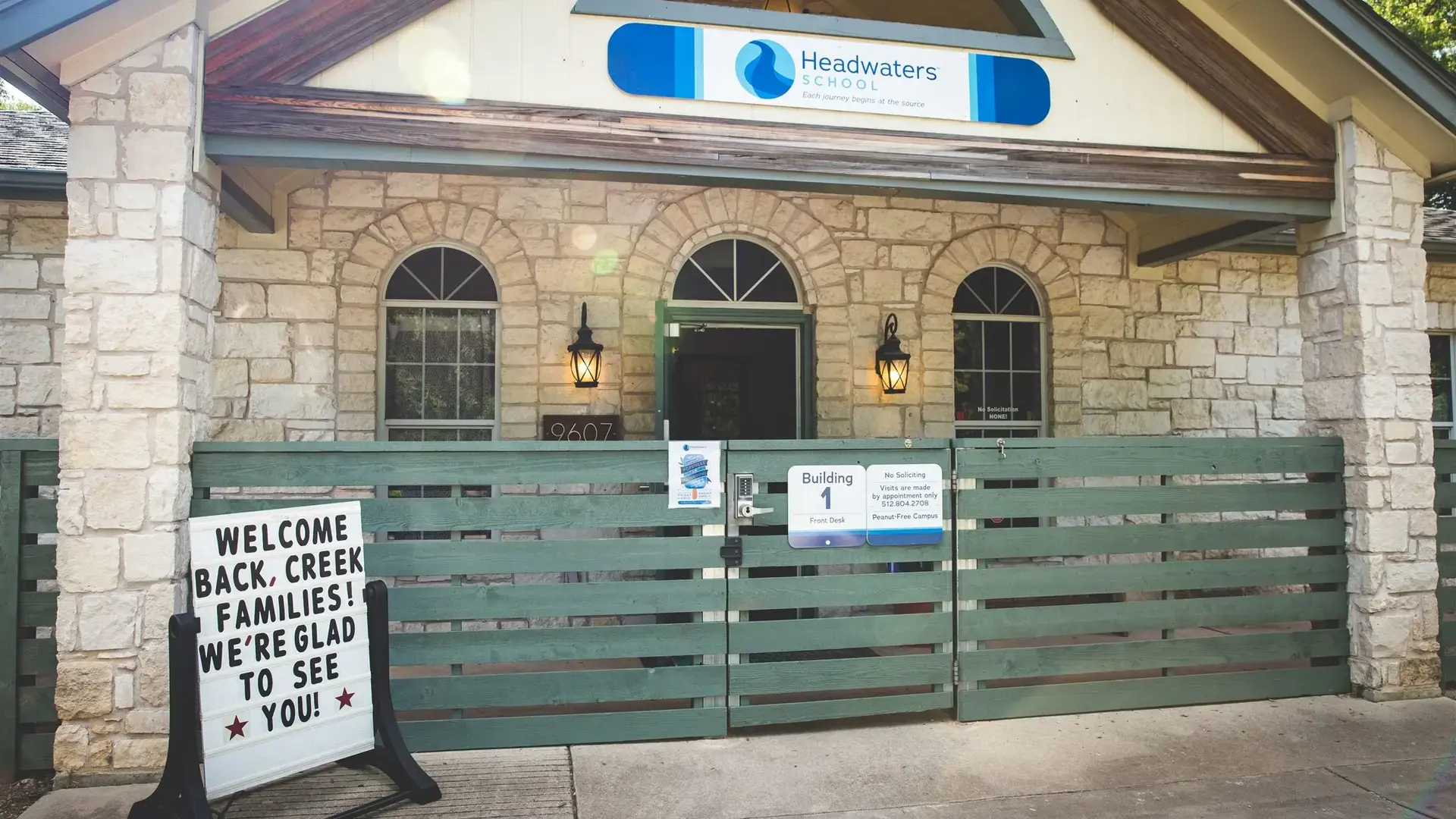 Green gated entrance to a Headwaters School building with a 'Welcome Back' sign.