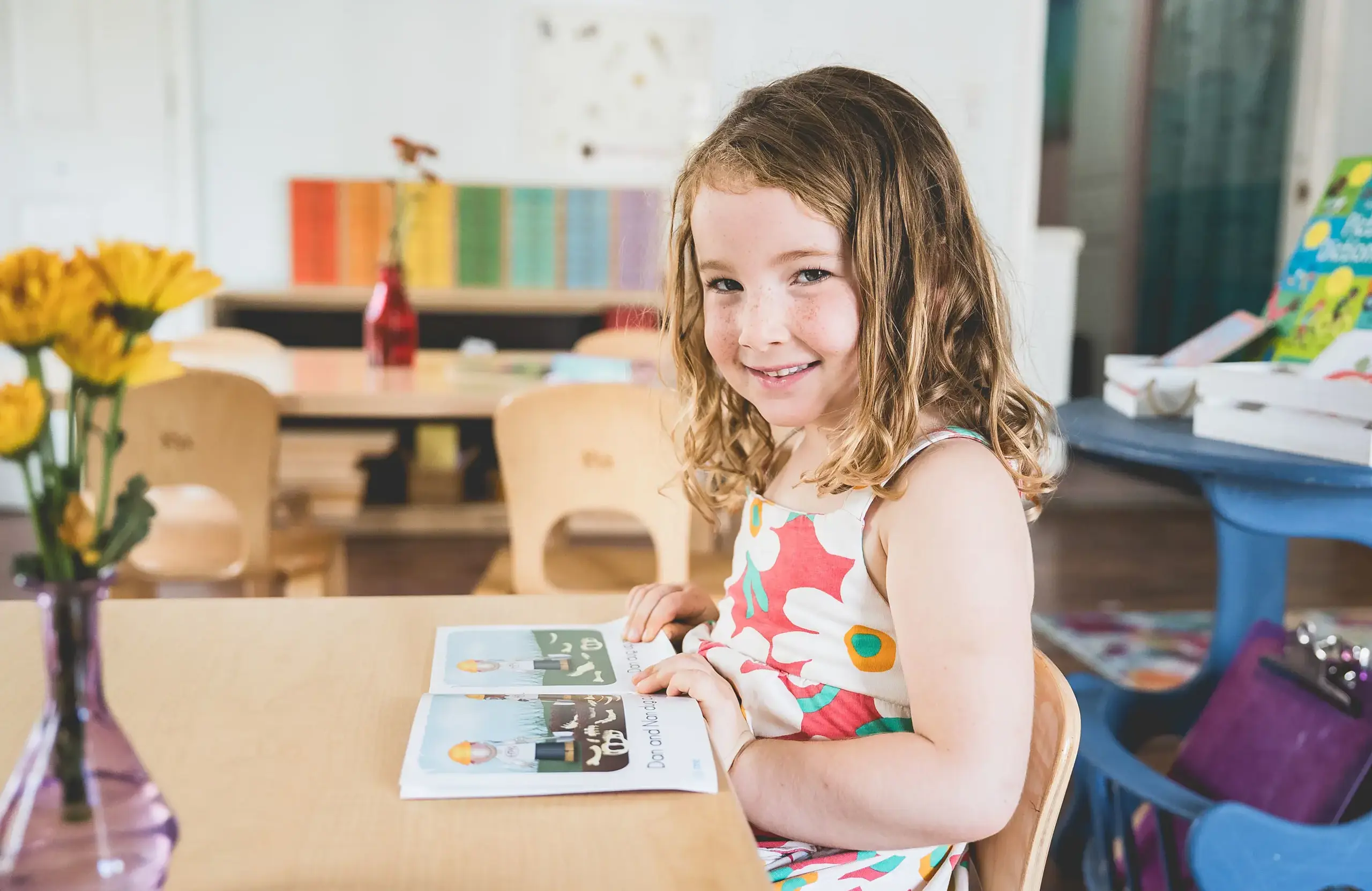 Primary student reading book in the classroom at a table