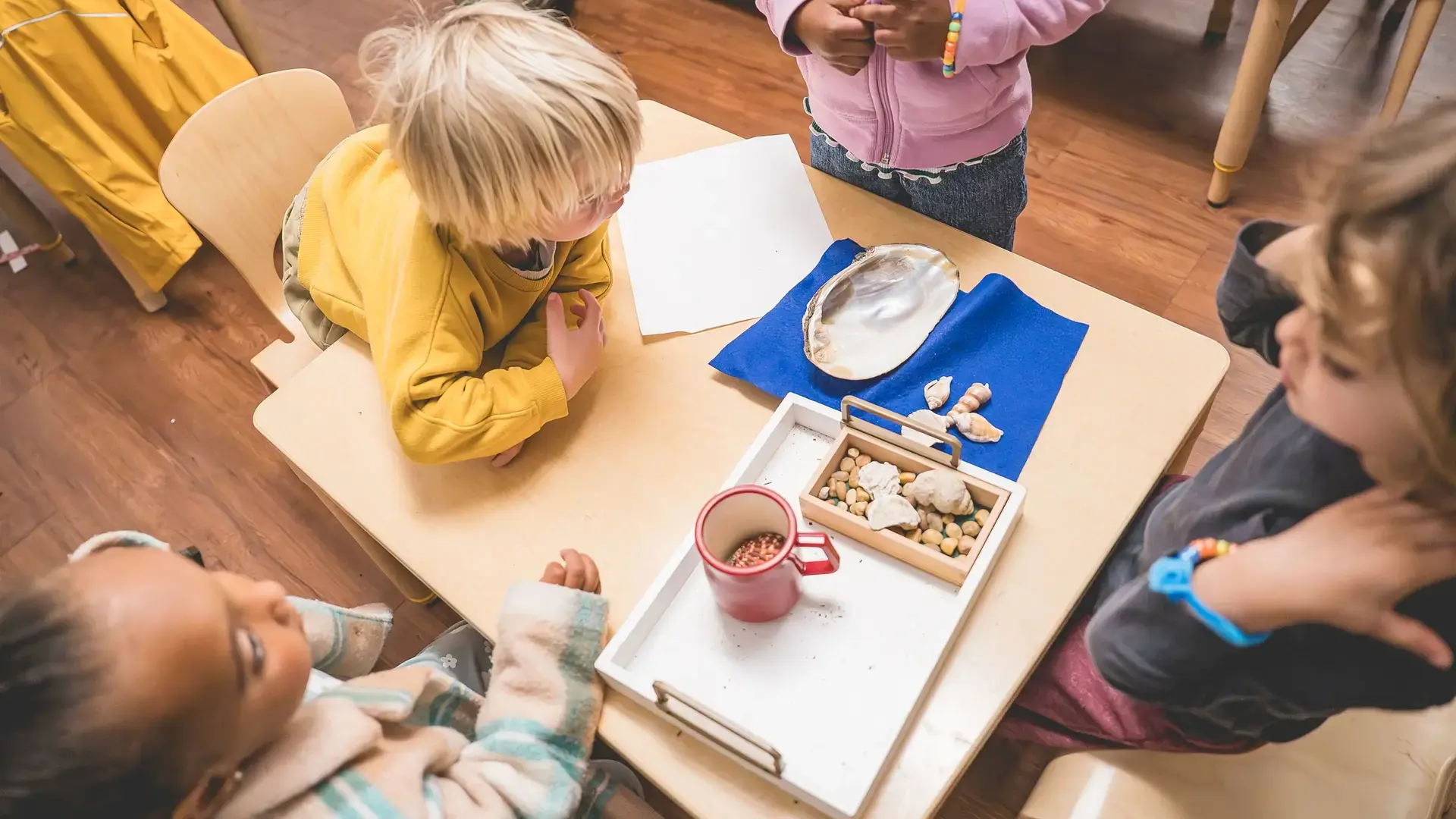 Overhead view of young children exploring hands-on learning materials at a table.