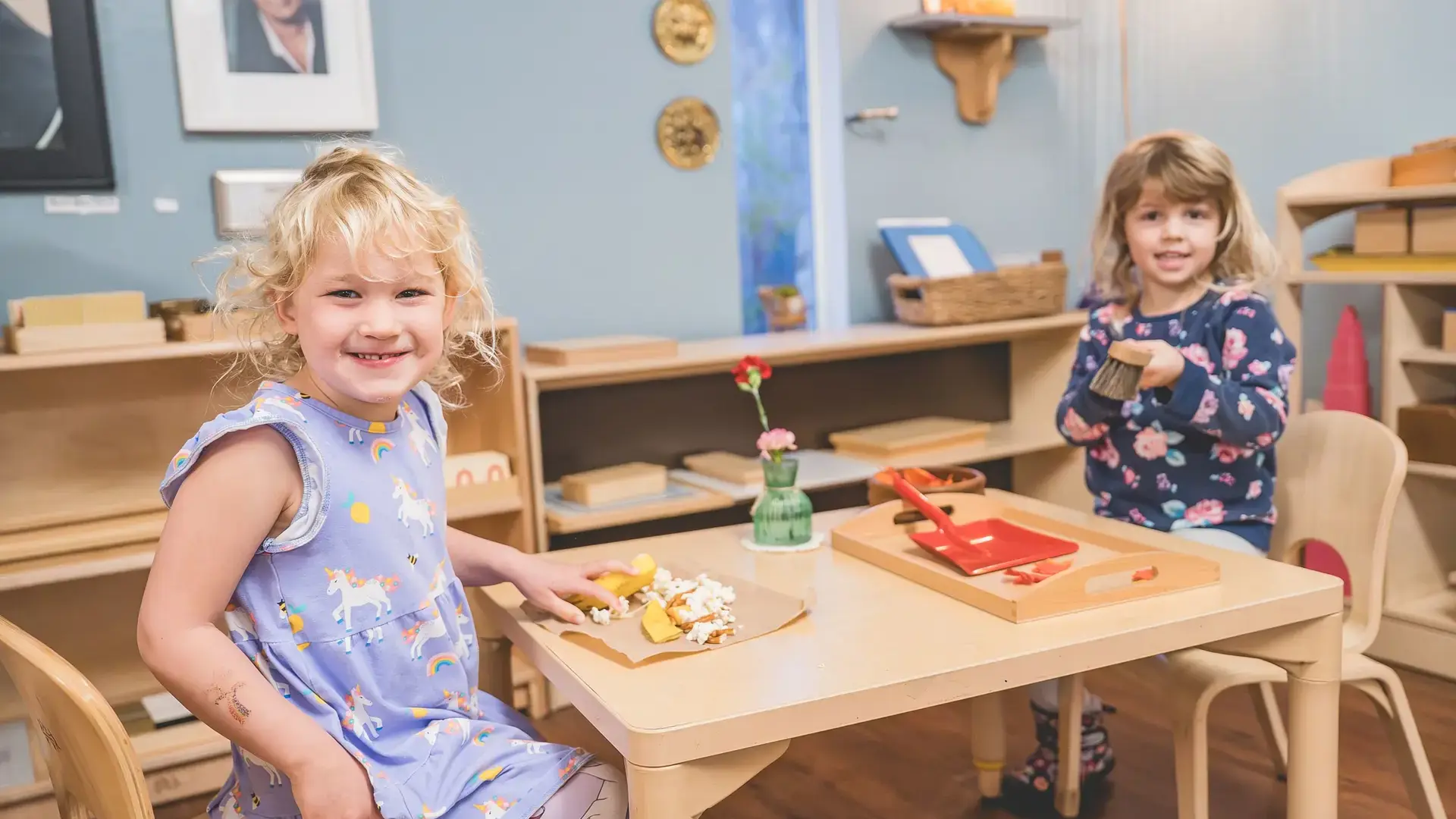 Two young children sitting together at a table with food.
