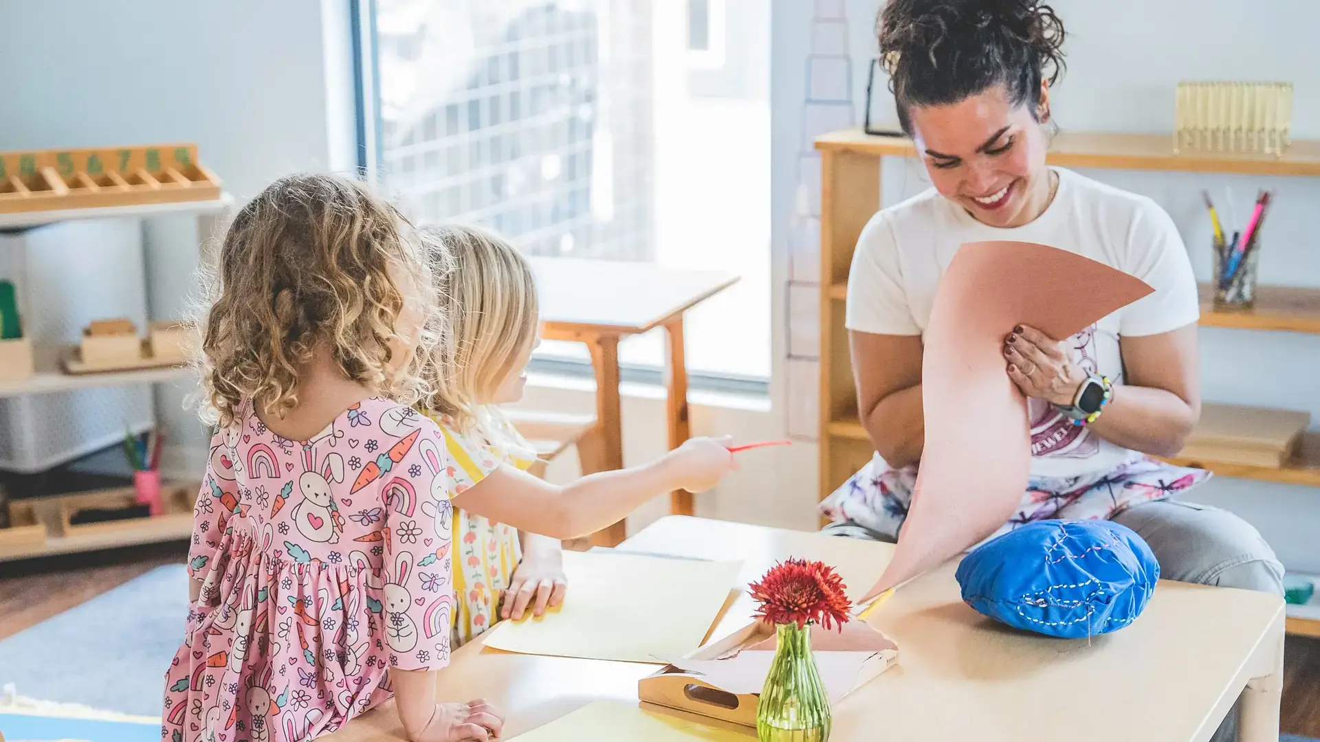 Early Childhood teacher guiding young students through a hands-on classroom activity.