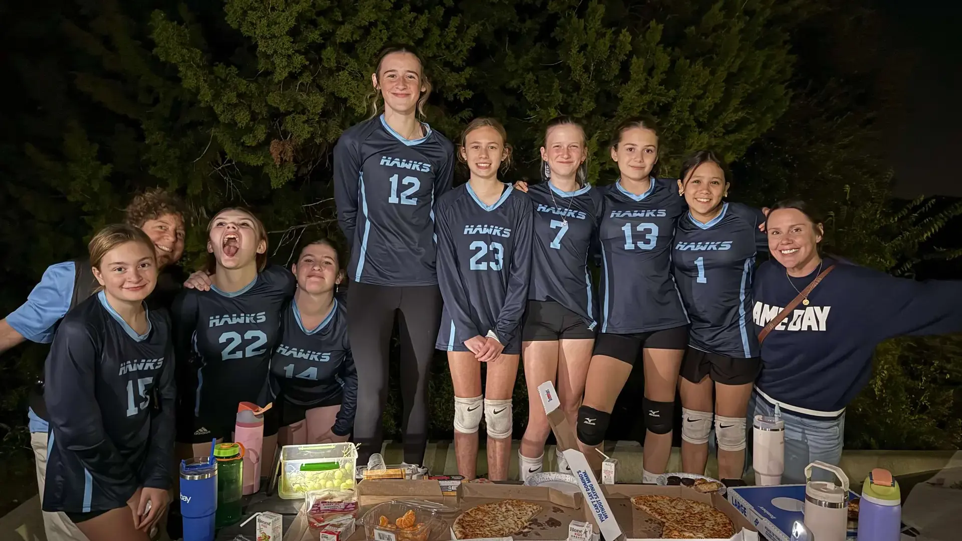 middle school girls volleyball team posing together after a match.'middle school girls volleyball team posing together after a match.
