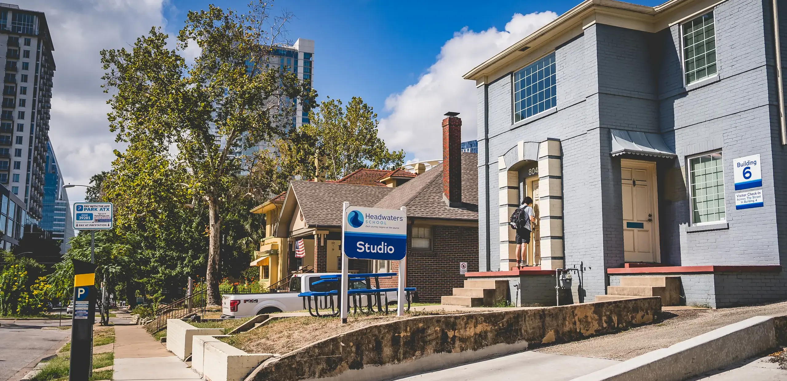 Street view of Headwaters School's Studio building signage with a student entering nearby Building 6.