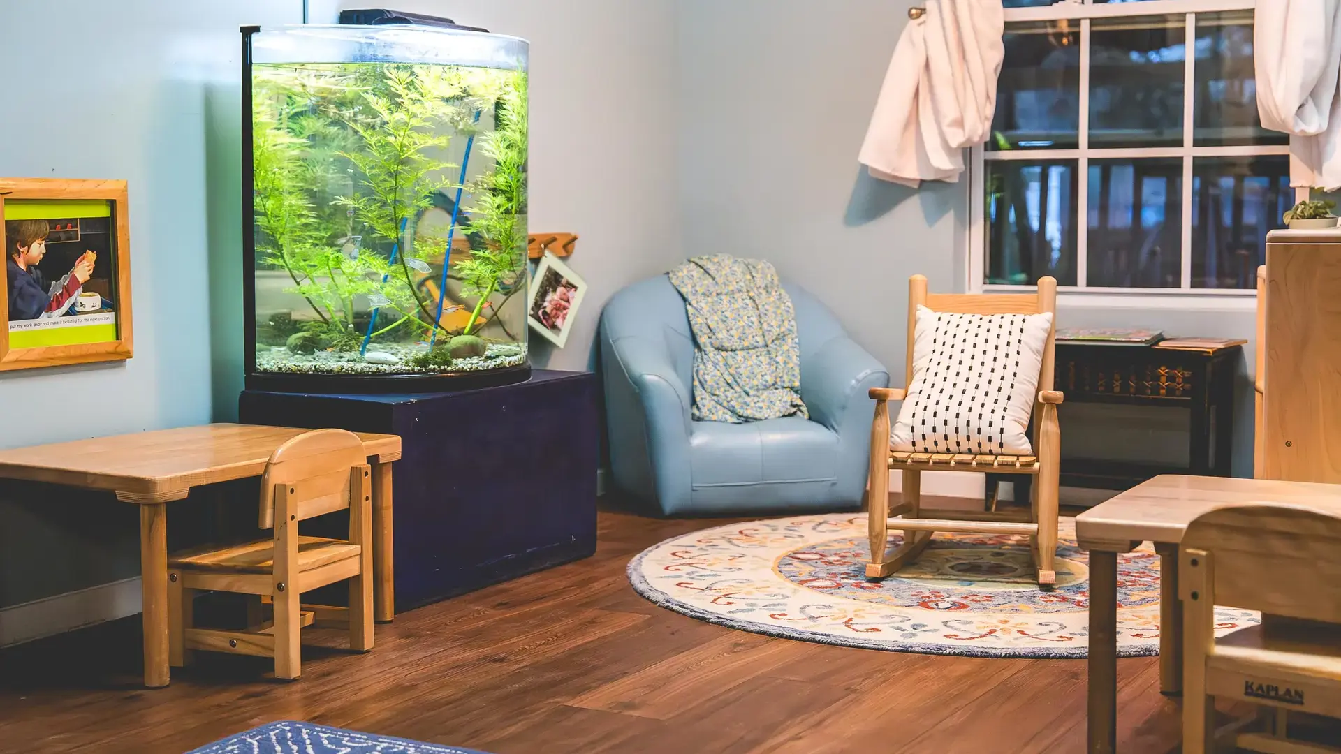 classroom reading corner with a fish tank, armchair, and round rug.