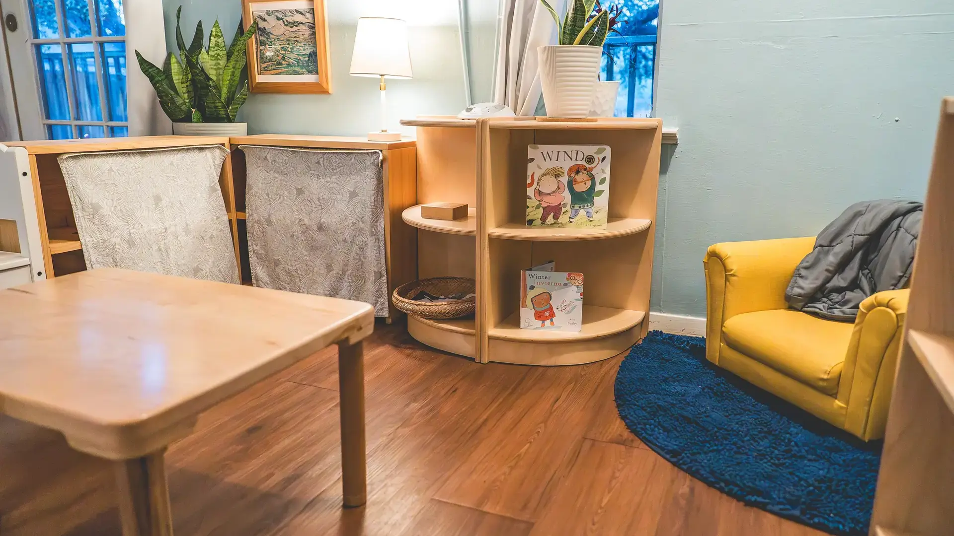Cozy classroom reading corner with a yellow armchair and low bookshelf.
